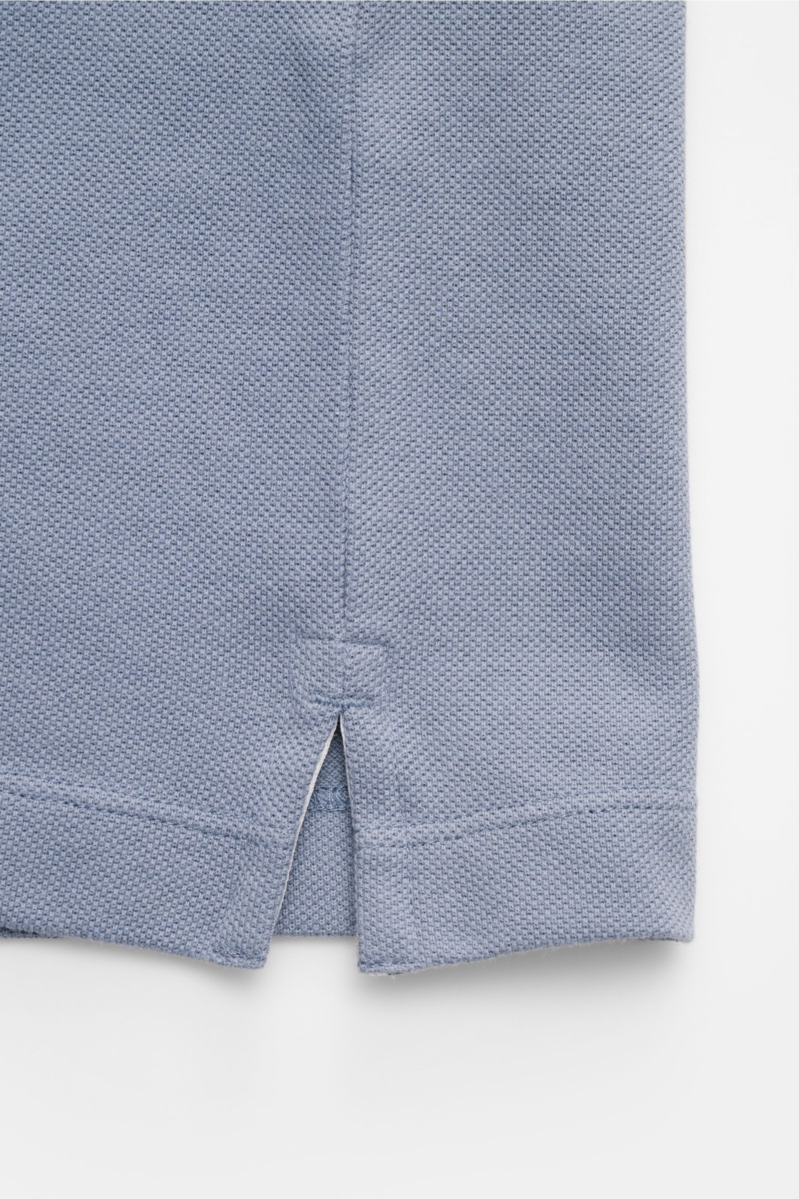 Nahaufnahme des seitlichen Saums mit Saumschlitz des Stone Island Poloshirts rauchblau aus Baumwoll-Piqué mit strukturierter Oberfläche.