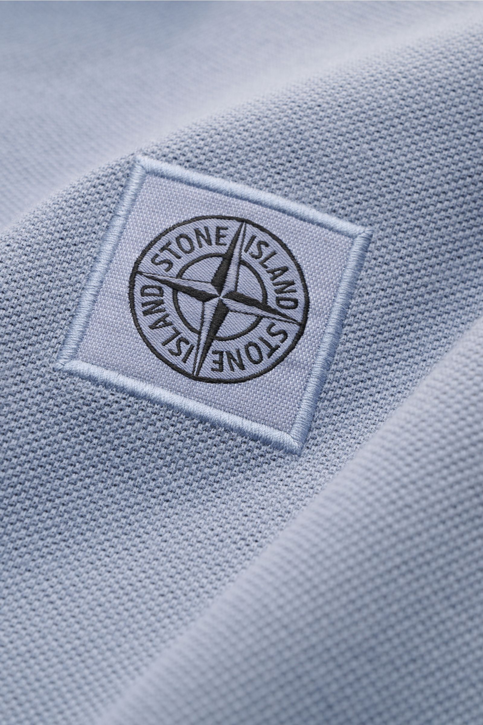 Stone Island Poloshirt rauchblau aus Baumwoll-Piqué mit STONE ISLAND-Weblabel, Nahaufnahme schräg von oben, strukturierter Griff