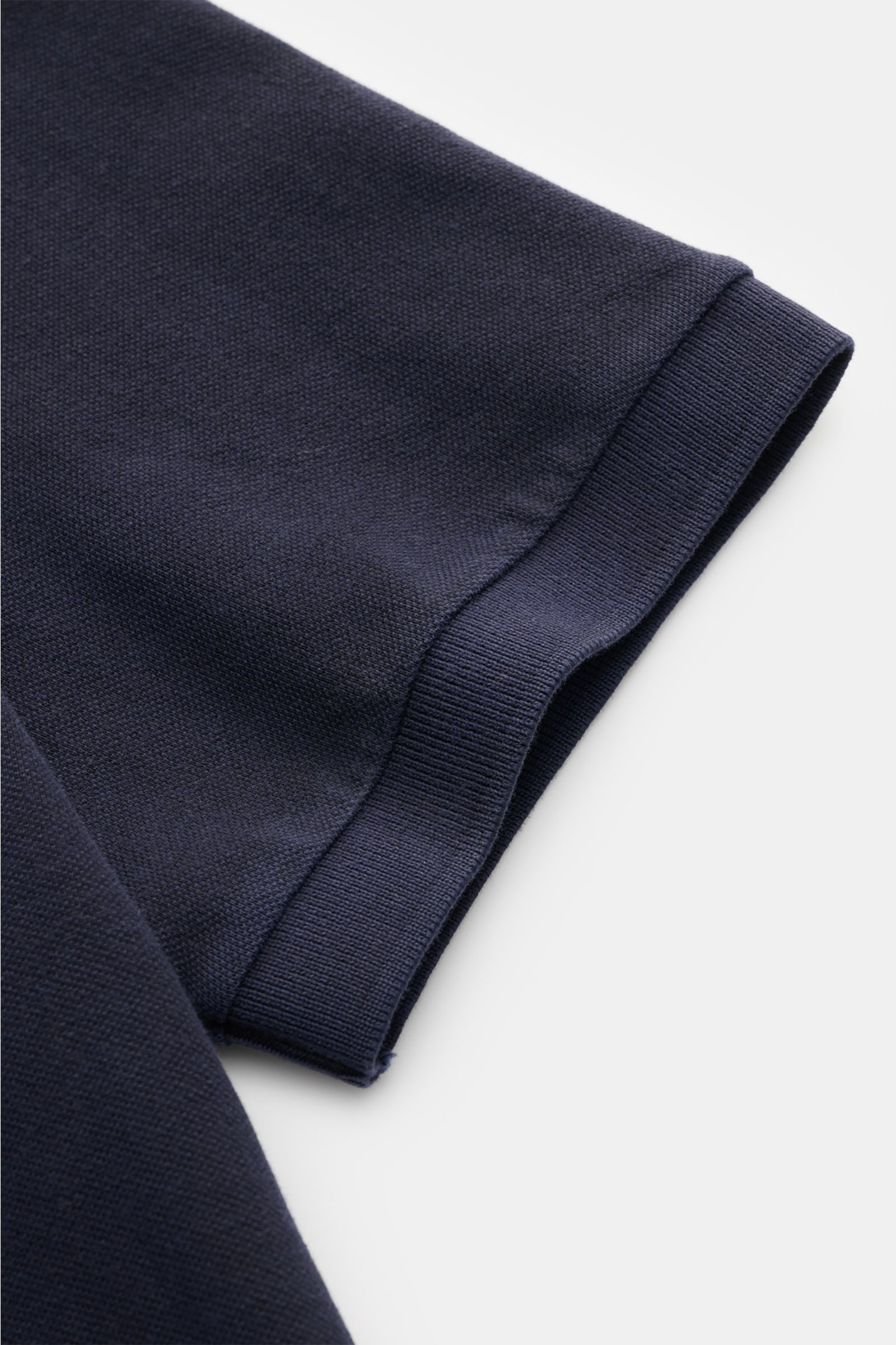 Nahaufnahme des Ärmels eines Stone Island Poloshirts navy aus Baumwoll-Piqué, slim fit, mit flexiblen Bündchen, seitlichem Saum.