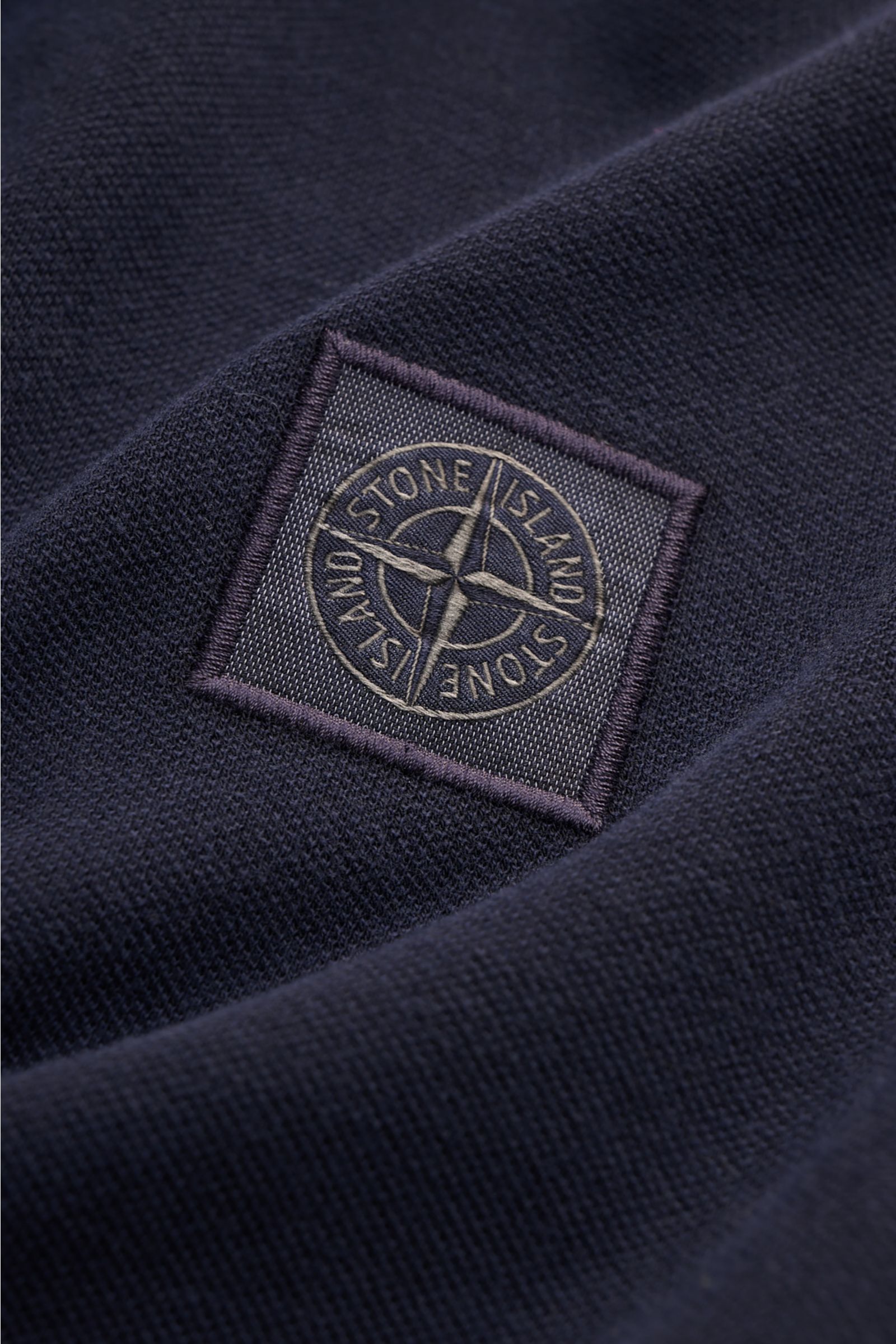 Nahaufnahme des Stone Island Poloshirts navy aus Baumwoll-Piqué, Detailansicht des Weblabels, strukturierter Griff, Slim Fit.