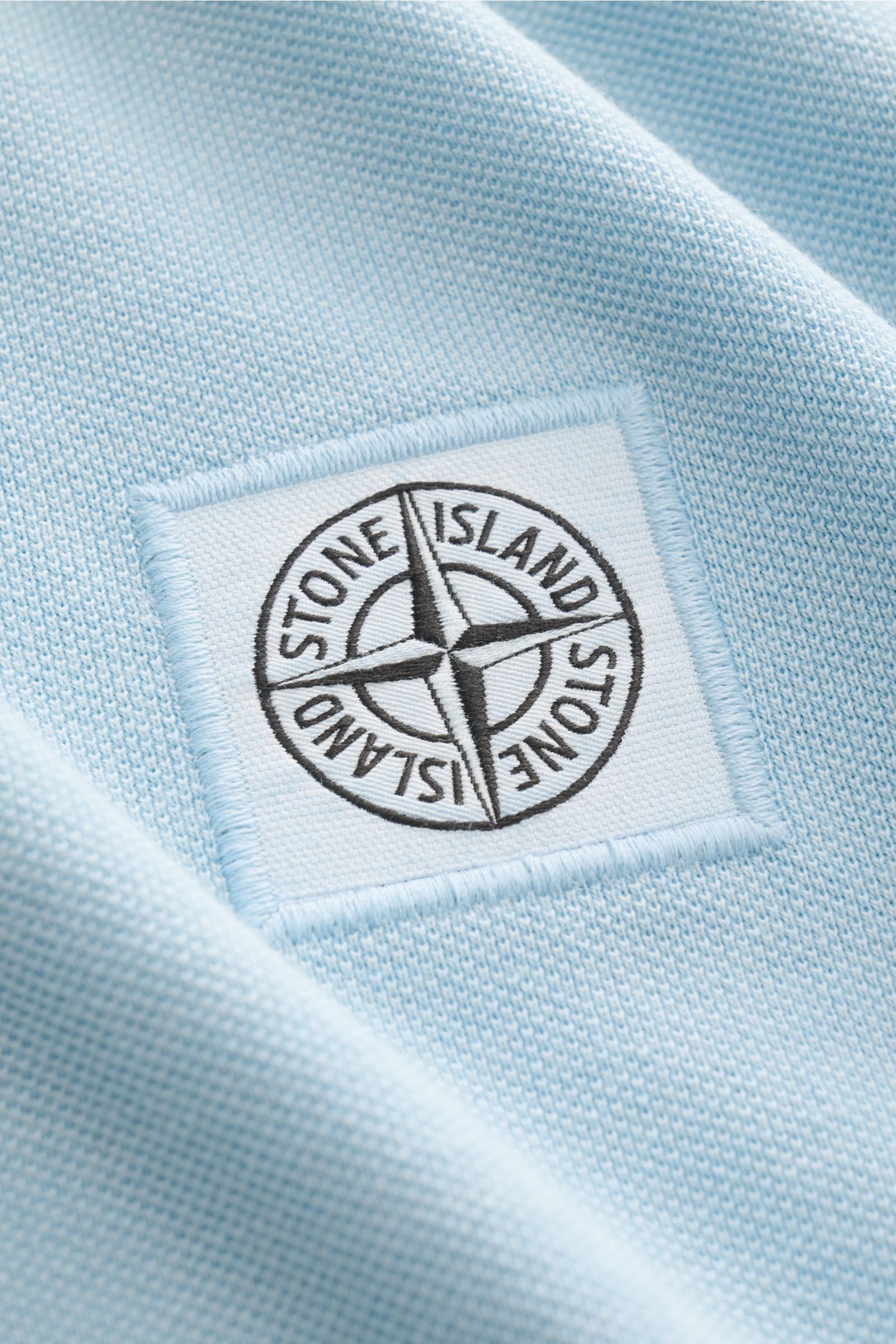 Stone Island Poloshirt hellblau aus Baumwoll-Piqué, Slim Fit, Close-up auf das Weblabel, strukturierter Griff, garment dyed.