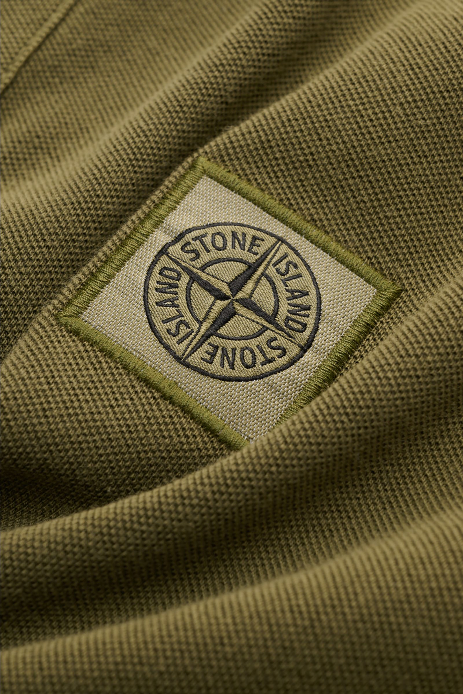 Nahaufnahme des Stone Island Poloshirt oliv aus Baumwoll-Piqué mit STONE ISLAND-Weblabel, strukturierter Griff und Slim Fit.