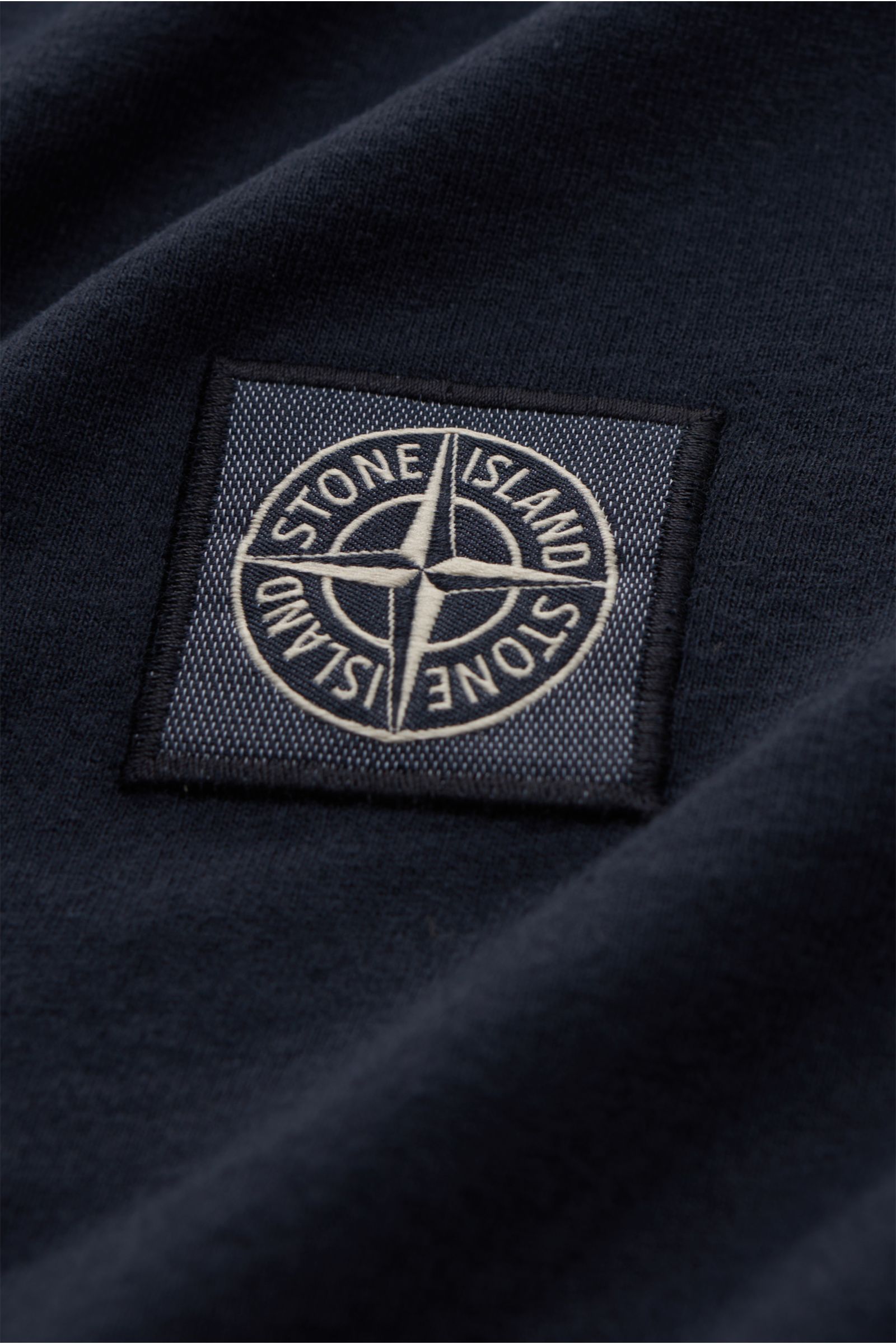 Close-up of the Stone Island Jersey-Poloshirt navy showing the STONE ISLAND-Weblabel on soft, pure cotton jersey fabric, photographed from a top-side perspective. Das leichte Poloshirt ist ein Must-have in der sportiven Herrengarderobe: Aus Baumwoll-Jerse