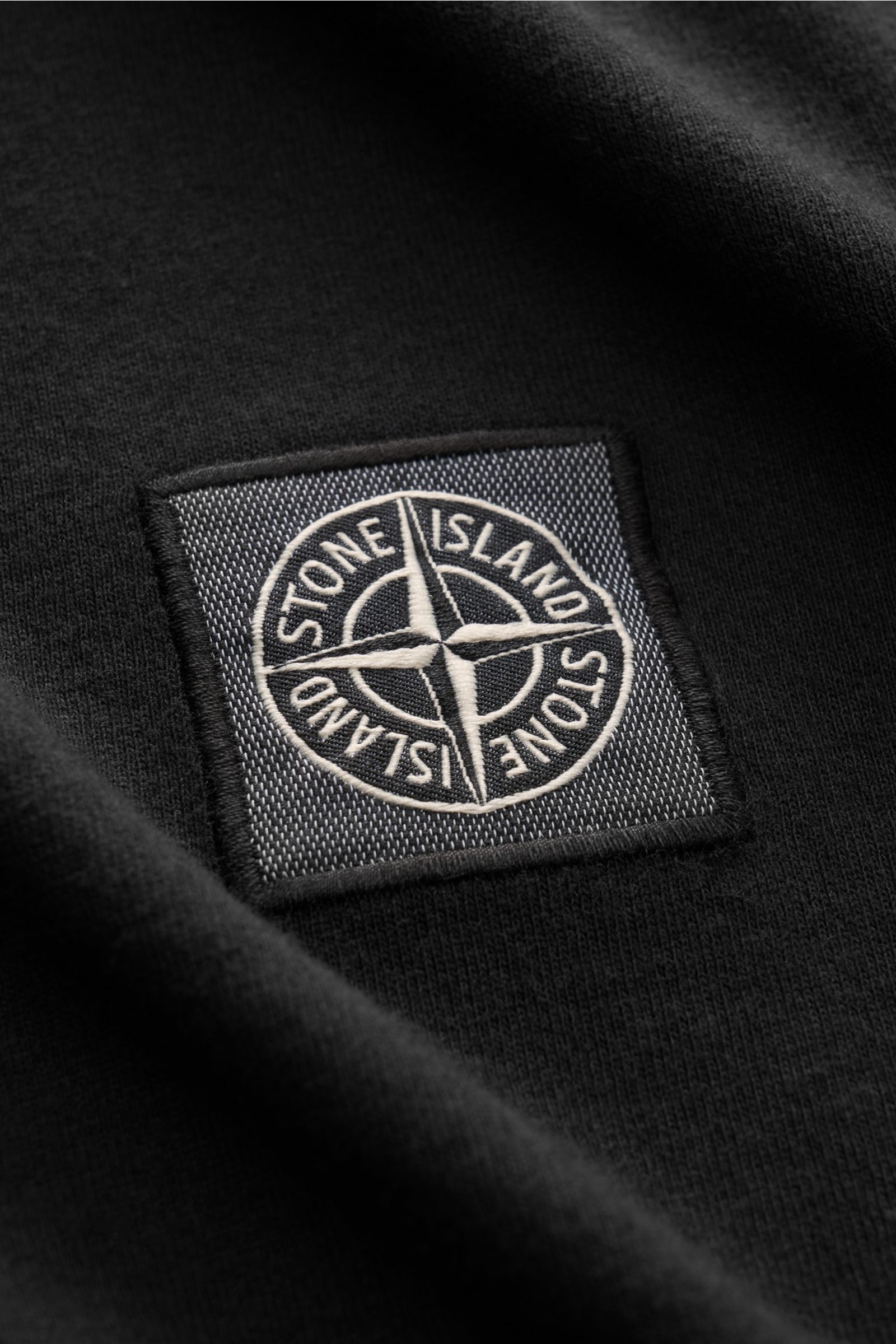 Close-up front view of the Stone Island Jersey polo shirt black showing the detailed fabric label on soft, black cotton jersey.