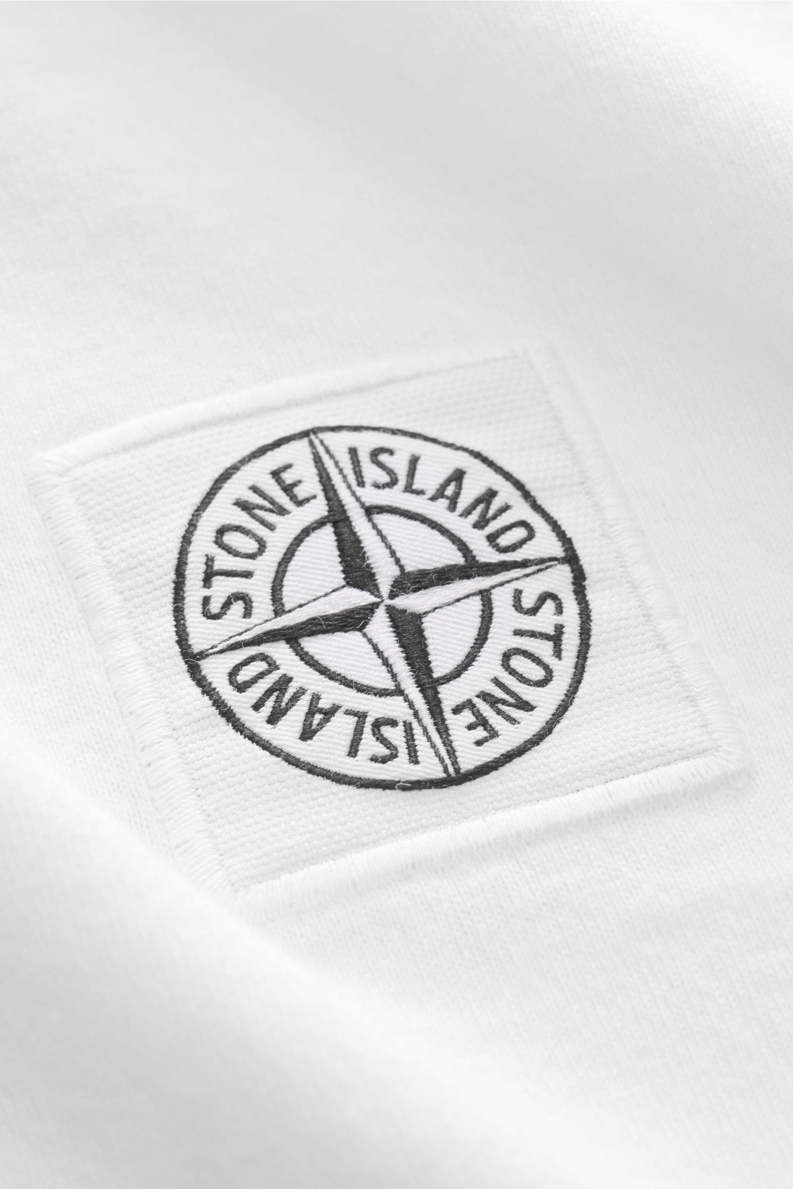 Nahaufnahme des weißen Stone Island Jersey-Poloshirt mit gesticktem Weblabel, weichem Baumwoll-Jersey, Slim Fit, Polokragen und Zwei-Knopf-Leiste.