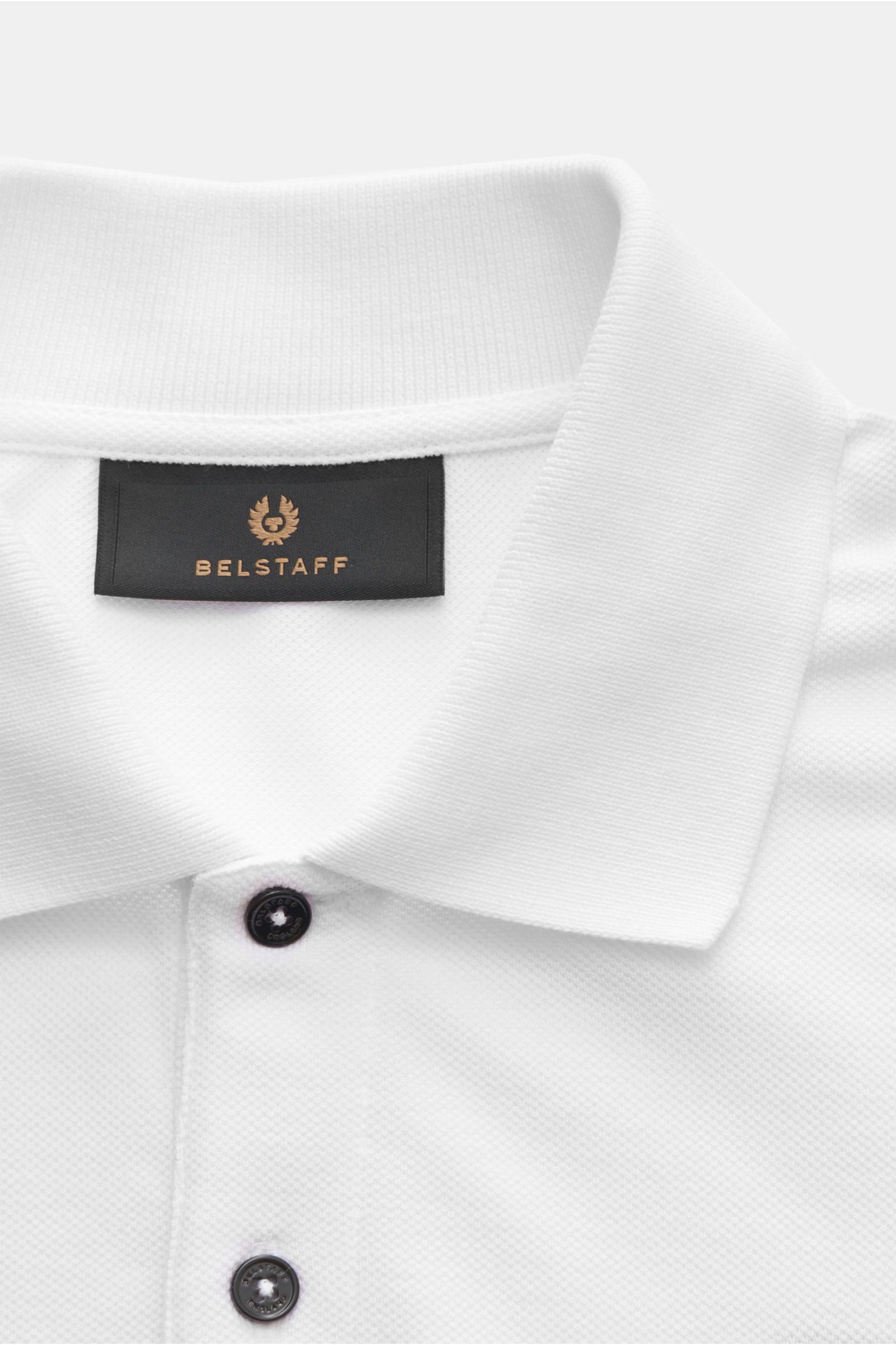 Close-up front view of Belstaff Poloshirt weiß showing the classic collar, two-button placket, and BELSTAFF logo label on chest; Piqué aus reiner Baumwolle, leicht strukturierter Griff, Slim Fit, Zwei-Knopf-Leiste, klassischer Polokragen, BELSTAFF-Weblabe