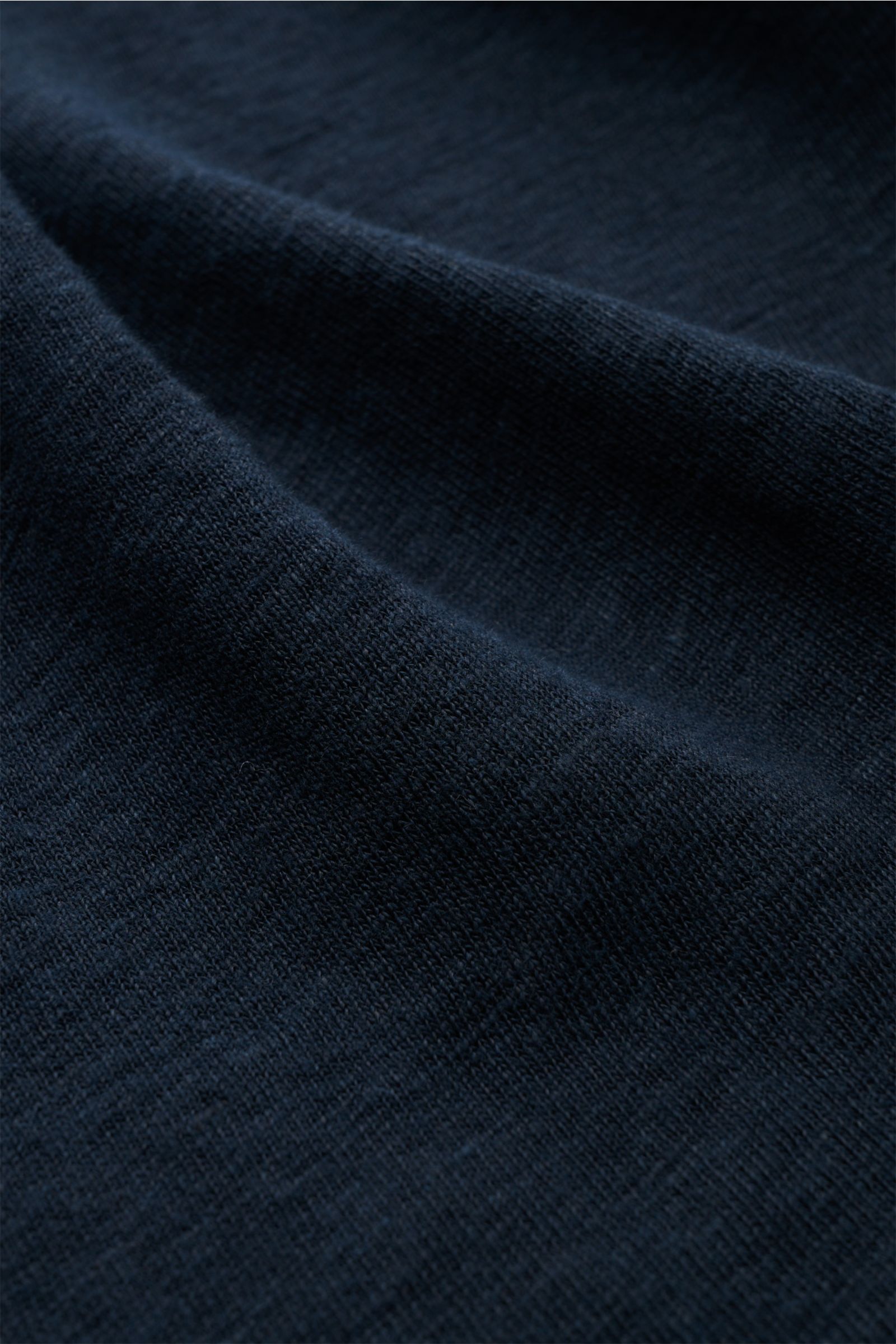 Detaillierte Nahaufnahme des stückgefärbten, elastischen Leinens des 04651/ A trip in a bag Leinen Jersey-Poloshirt navy, aufgenommen aus schräger Perspektive, zeigt die fein strukturierte, atmungsaktive Jersey-Qualität mit geschmeidigem Griff.
