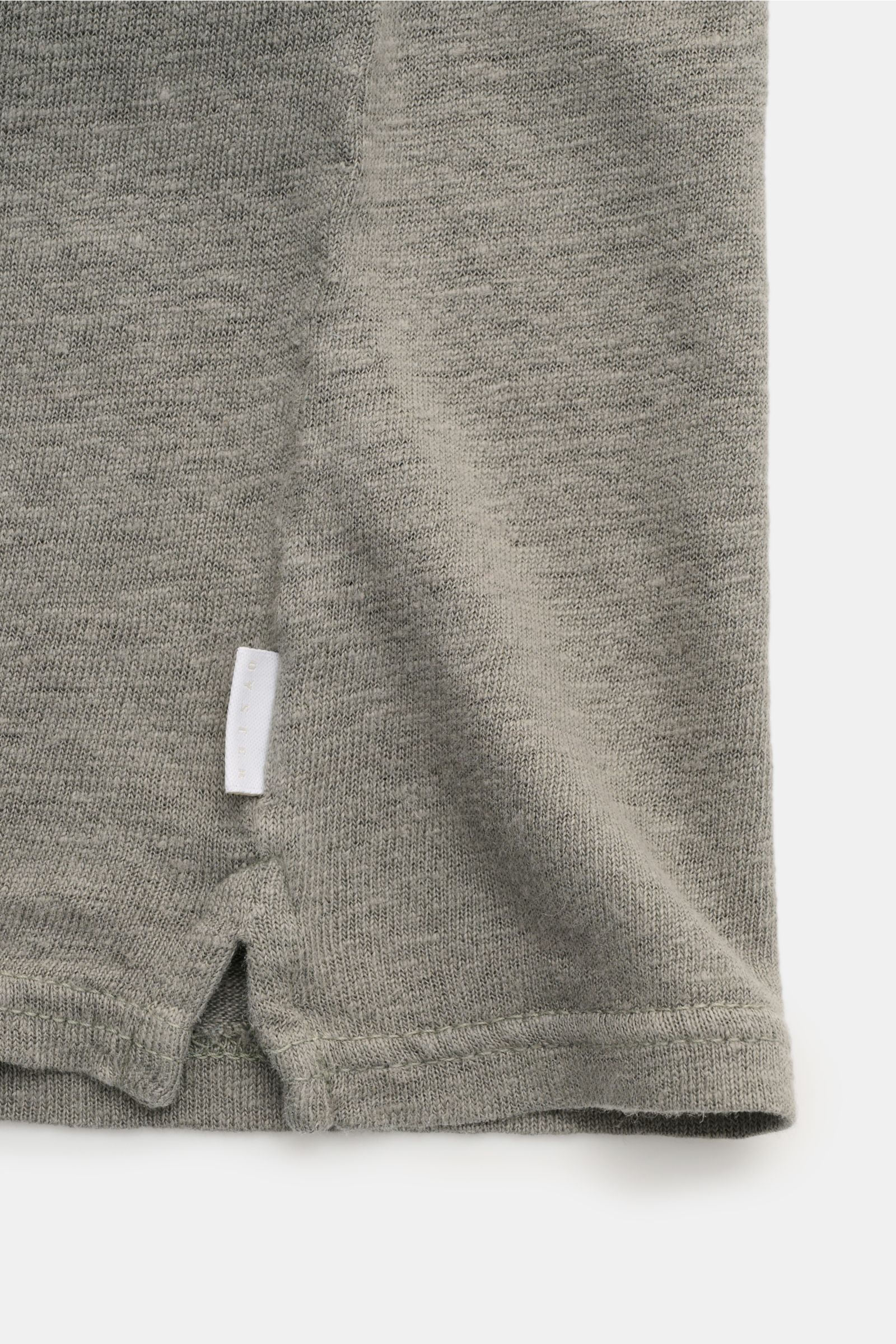 04651/ A trip in a bag Leinen Jersey-Poloshirt graugrün, Detailansicht Saum mit kurzem Schlitz und kleinem Weblabel in leichter, elastischer Qualität.