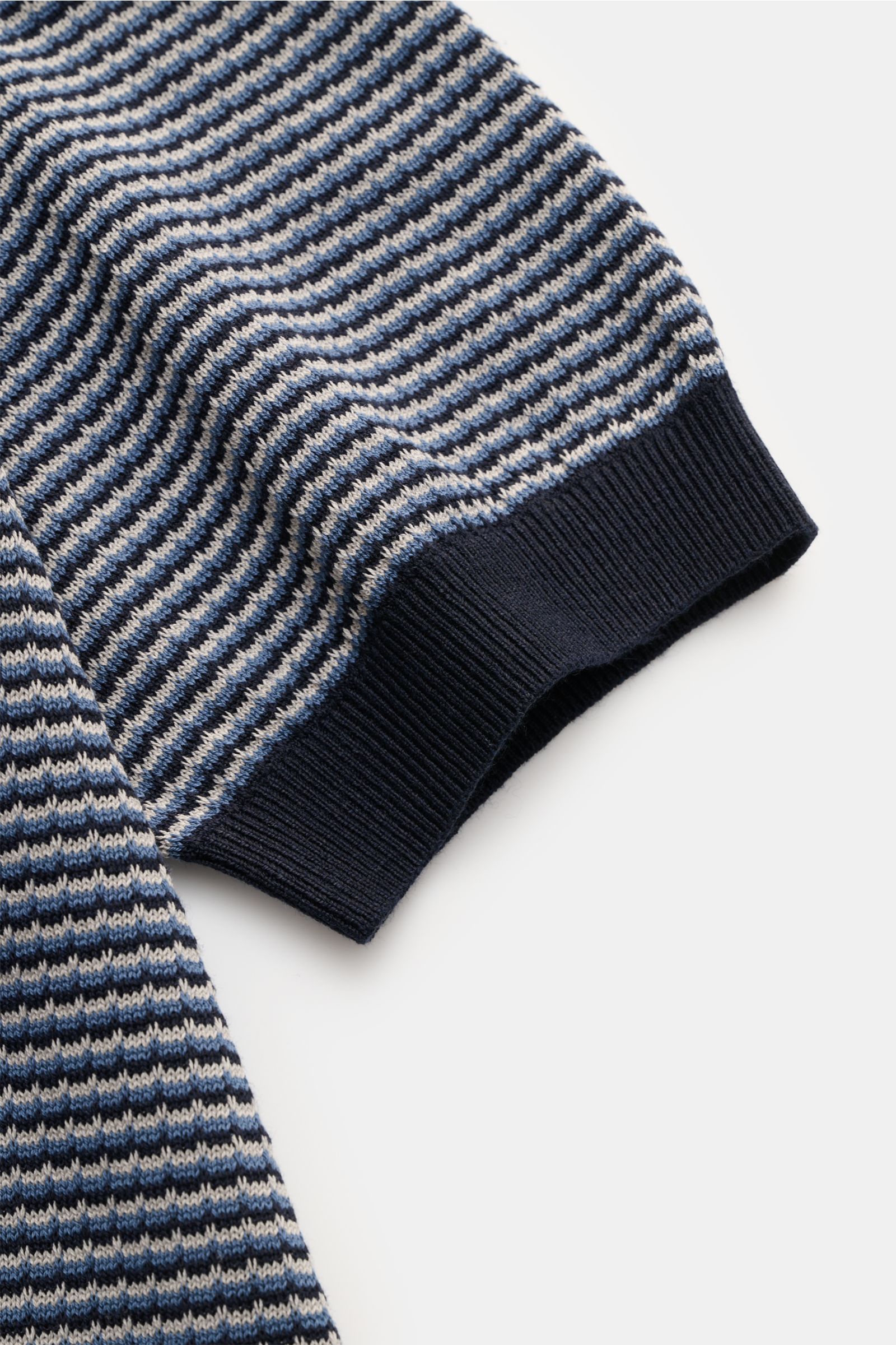 Close-up image of the sleeve of the Agnona Kurzarm-Strickpolo navy/rauchblau/hellgrau gestreift, photographed from above showing the fine knit stripe pattern and ribbed cuff. Für lässige Sommeroutfits: Das Kurzarm-Strickpolo von AGNONA besticht mit unverg