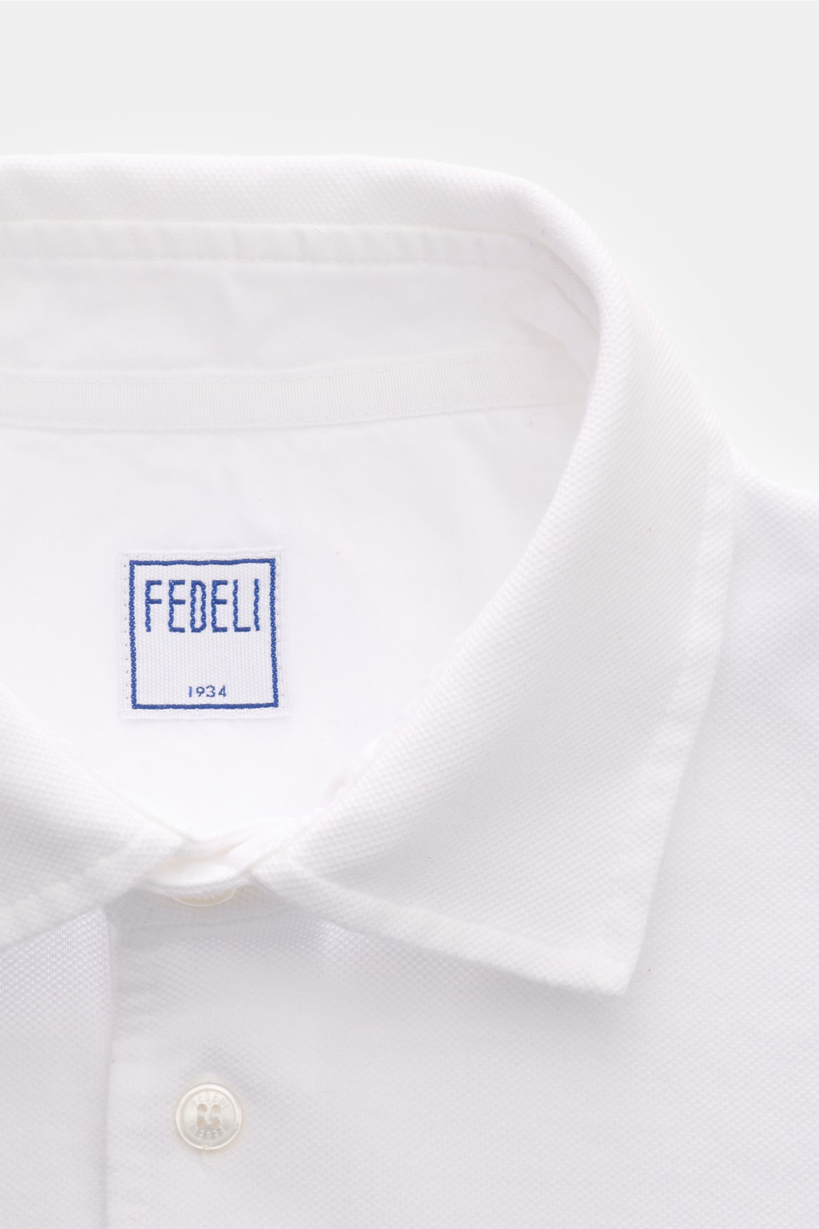 Nahaufnahme des weißen Fedeli Poloshirts 'North' von vorne oben, aus Baumwoll-Piqué, Slim Fit, garment dyed, mit Polokragen und Perlmuttknöpfen.