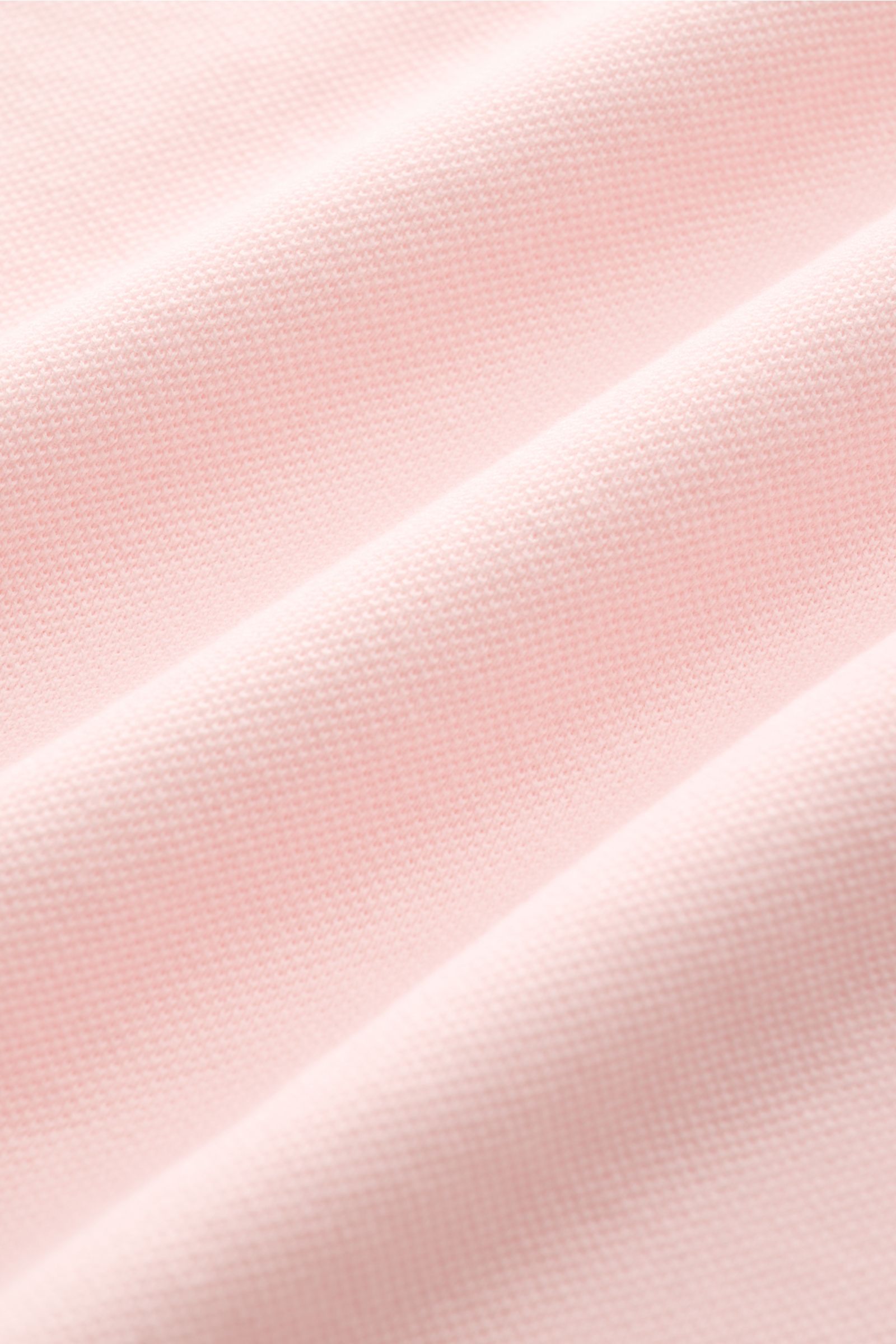 Fedeli Poloshirt 'North' rosé im Detail, Nahaufnahme des weichen, garment dyed Baumwoll-Piqué mit typischer Struktur aus schräger Perspektive.