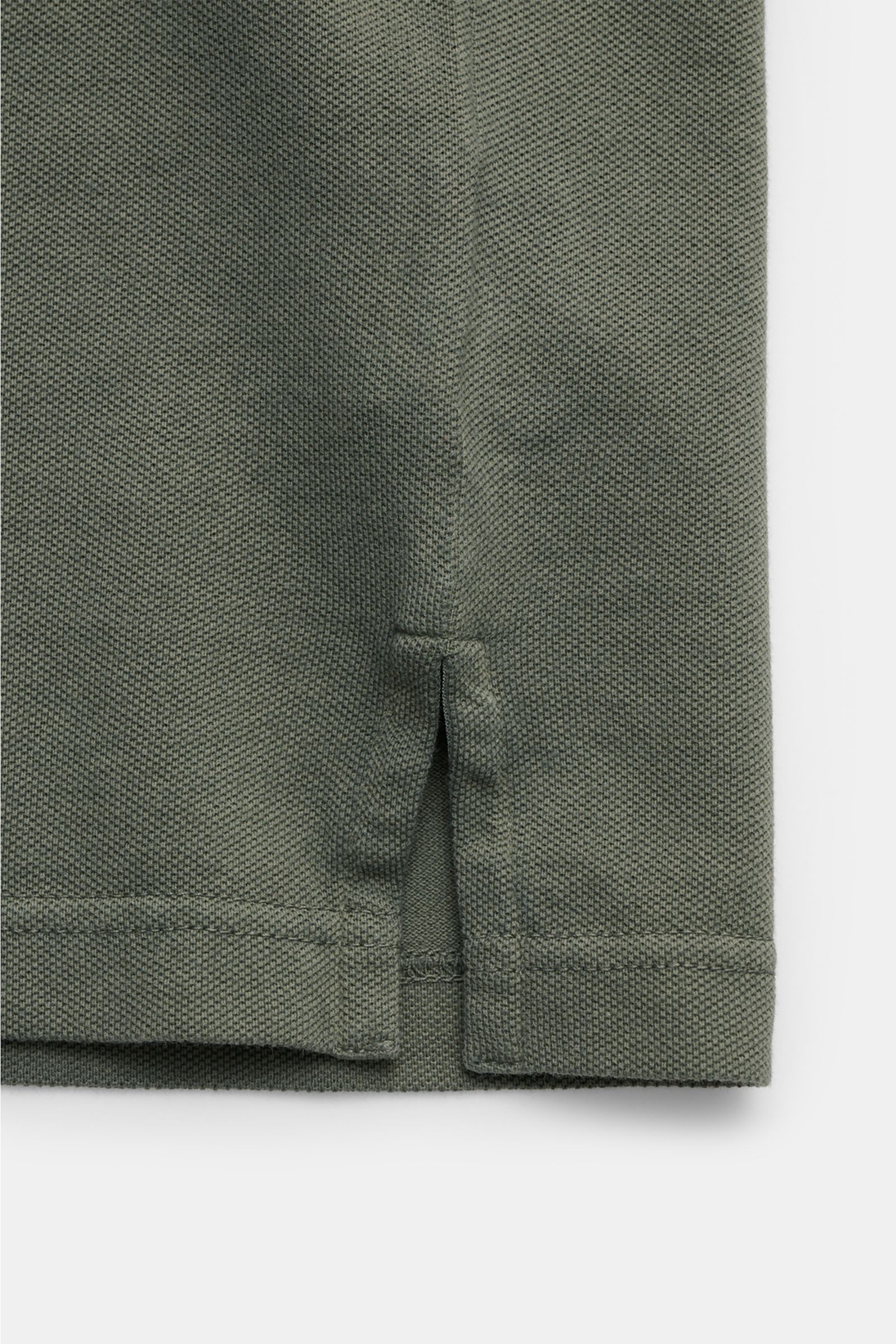 Close-up of the hem side slit of the Fedeli Poloshirt 'North' graugrün, showing the soft, garment-dyed cotton piqué fabric from a front-side perspective. Quiet Luxury: Das cleane Poloshirt 'North' aus hochwertigem Baumwoll-Piqué von FEDELI kommt ganz o
