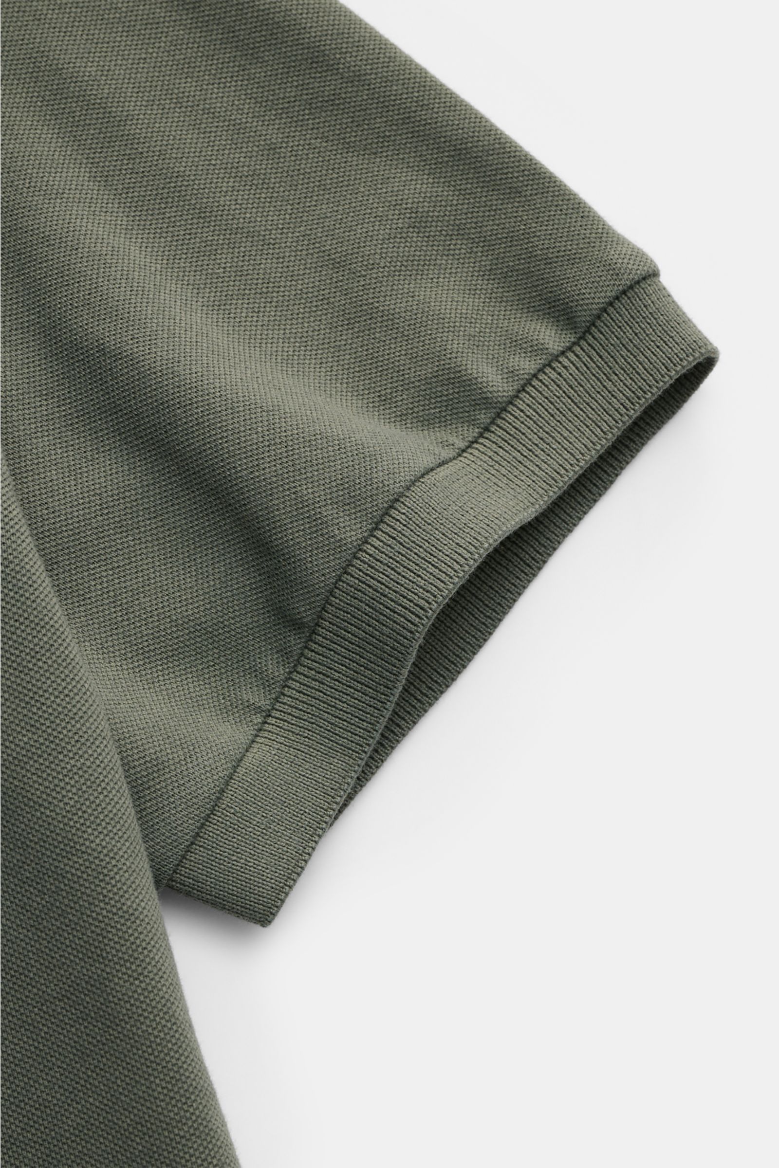 Close-up of the sleeve of the Fedeli Poloshirt 'North' graugrün, showing fine cotton piqué texture and ribbed cuff from a top-down perspective. 

Quiet Luxury: Das cleane Poloshirt 'North' aus hochwertigem Baumwoll-Piqué von FEDELI kommt ganz ohne Logo
