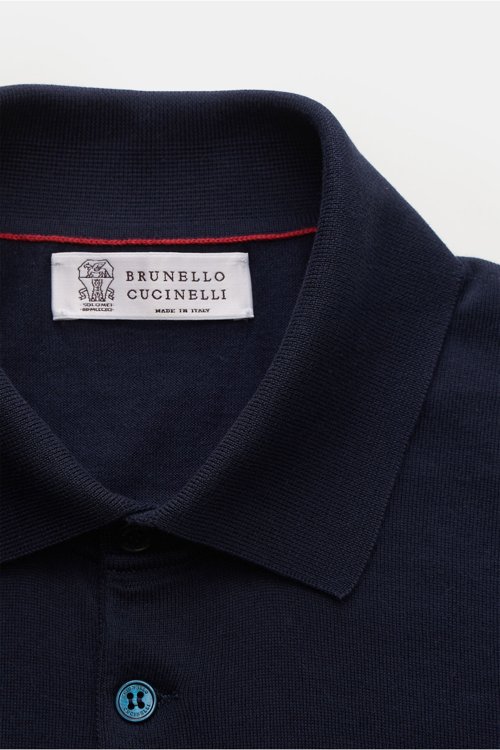 Close-up front view of Brunello Cucinelli Short sleeve knit polo shirt navy showing collar, label, and top button in fine knit fabric.

This timeless short-sleeved polo shirt from BRUNELLO CUCINELLI features a lightweight, fine knit fabric made from su