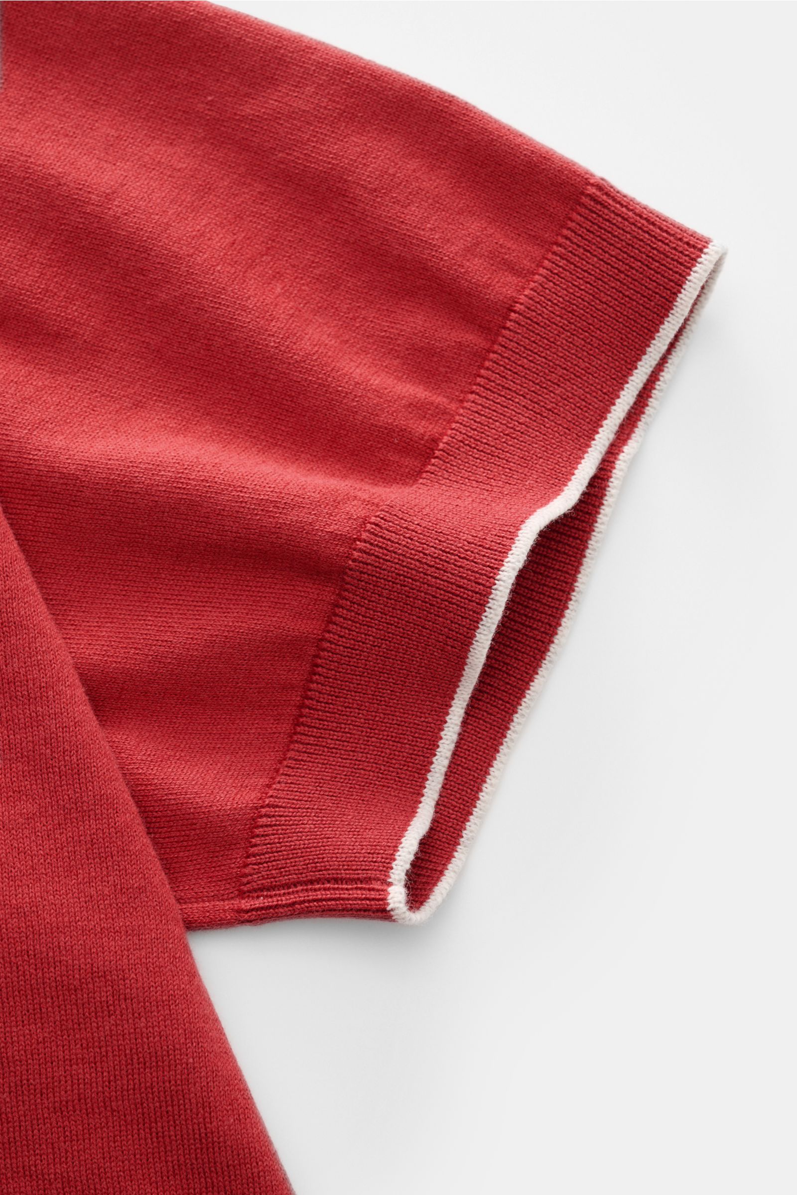 Close-up side view of the sleeve of the Brunello Cucinelli Kurzarm-Strickpolo rot, showcasing fine cotton knit, soft touch, slim fit, classic polo collar, three-button placket, narrow contrast edges, and flexible rib cuffs. Luxuriöse Alltags-Looks prof