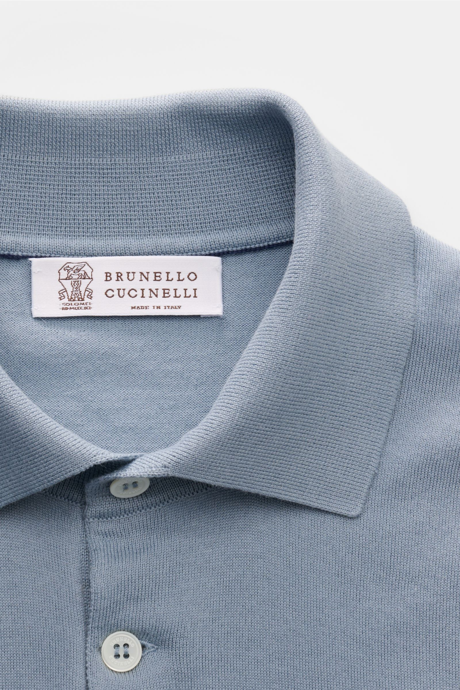 Close-up image from above showing the collar and buttons of the Brunello Cucinelli Kurzarm-Strickpolo rauchblau, a slim fit polo made of soft, fine knit pure cotton with classic collar, three-button placket, narrow contrasting edges, and flexible ribbed c
