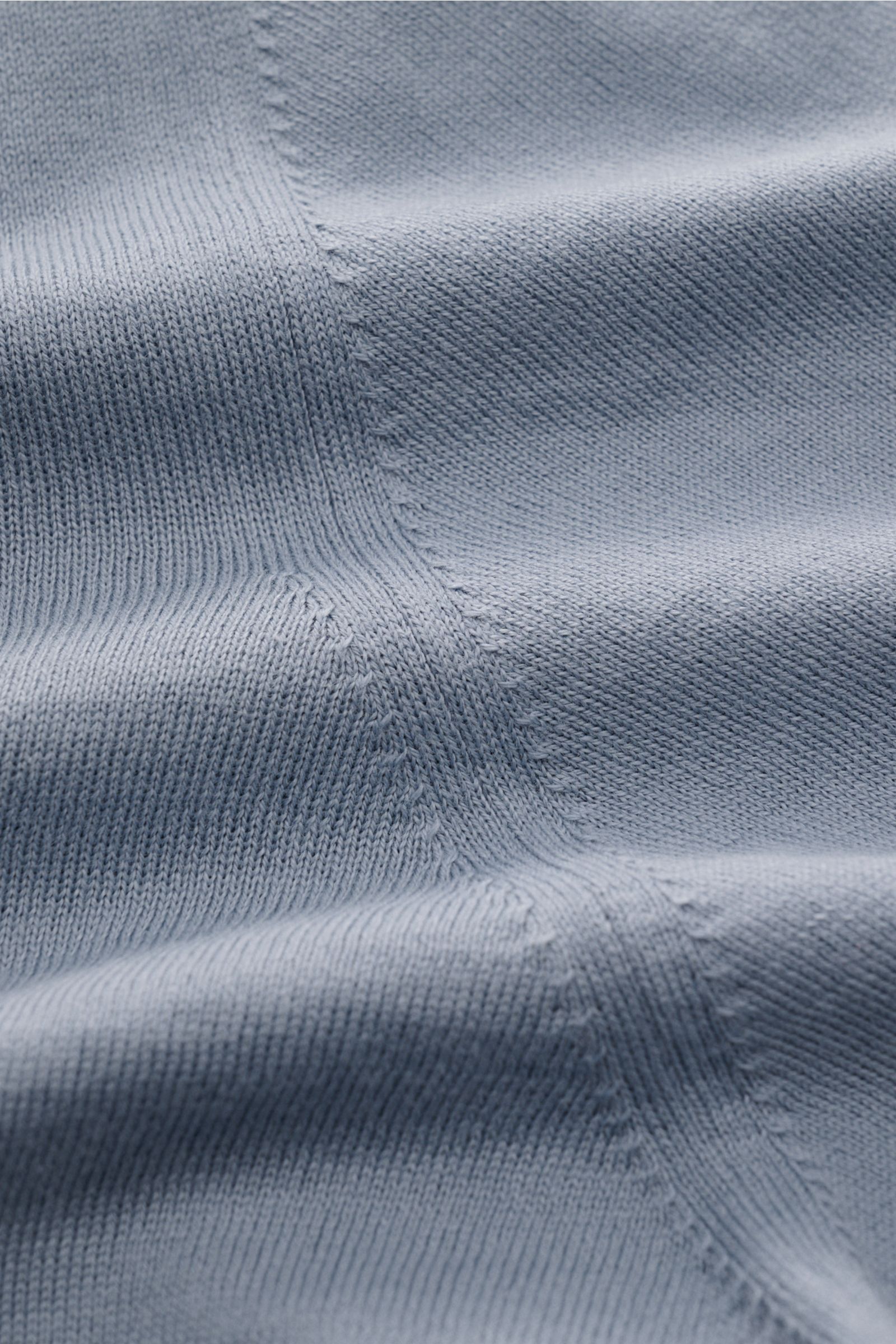 Close-up image of the fine knit texture of the Brunello Cucinelli Kurzarm-Strickpolo rauchblau, photographed from above showing soft cotton fabric with detailed seams and smooth surface. Luxuriöse Alltags-Looks profitieren von der leichten Strickqualit