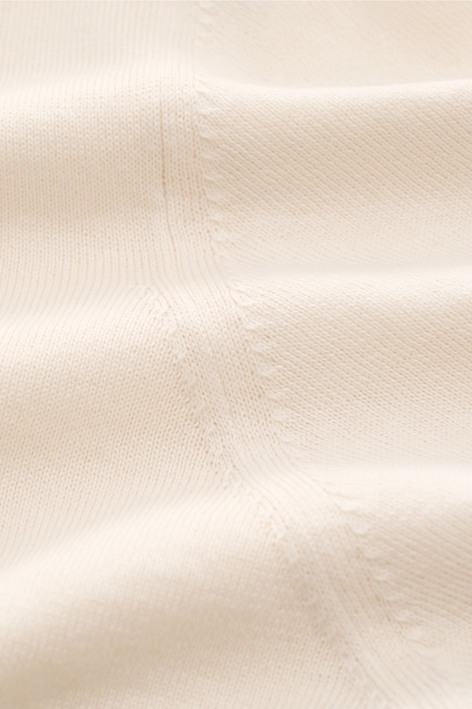 Close-up view of the creamy fabric texture and fine knit details of the Brunello Cucinelli Kurzarm-Strickpolo creme, showcasing its soft cotton material and delicate stitching. Luxuriöse Alltags-Looks profitieren von der leichten Strickqualität dieses zei