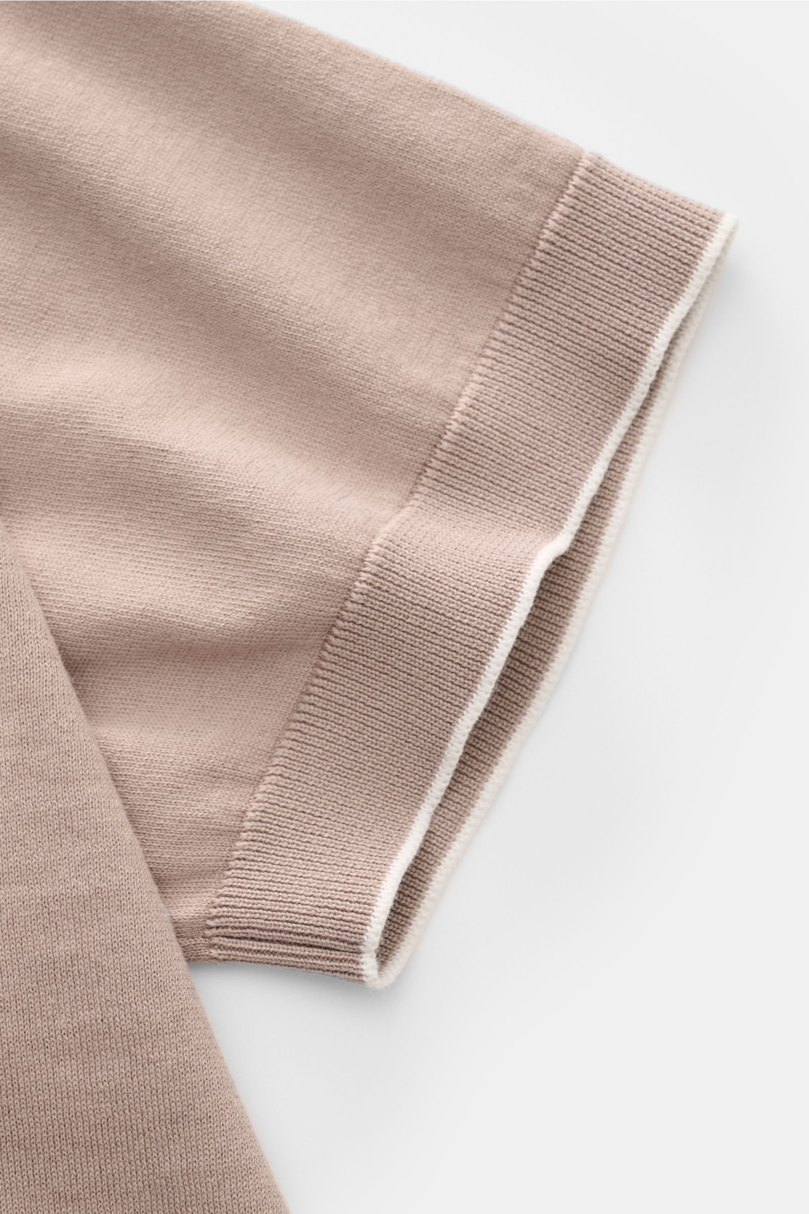 Close-up of the sleeve of the Brunello Cucinelli Kurzarm-Strickpolo taupe, showing fine cotton knit, slim fit, and narrow contrast edges from a top-down perspective. Luxuriöse Alltags-Looks profitieren von der leichten Strickqualität dieses zeitlosen K