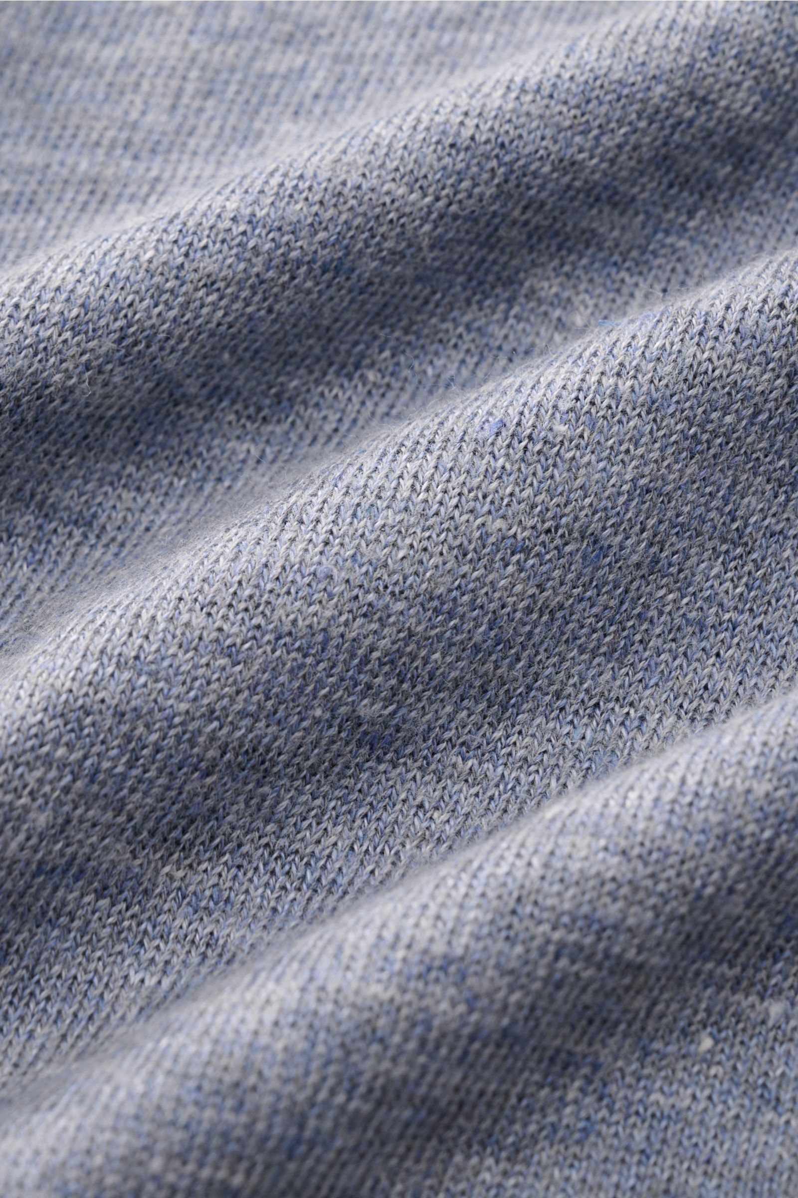 Close-up from a top angle of the textured fabric of the Brunello Cucinelli Kurzarm-Strickpolo rauchblau meliert, showing its fine knit and light grain. Mit seinem luftigen Mix aus Leinen und Baumwolle bietet dieses stilvolle Strickpolo von BRUNELLO CUC