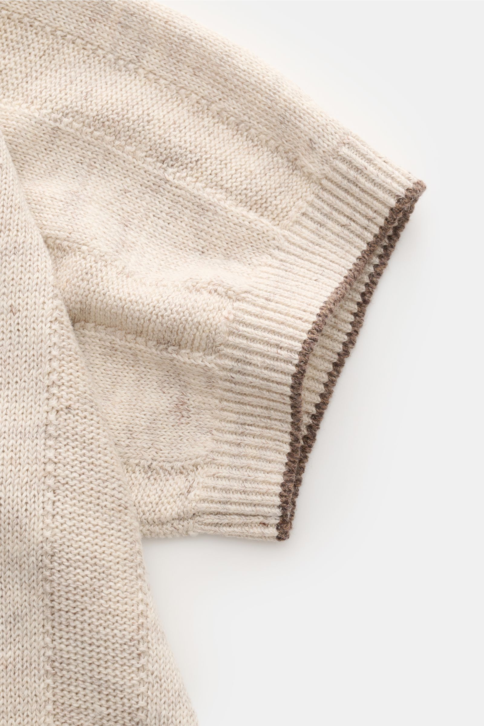 Close-up of the sleeve of the Brunello Cucinelli Kurzarm-Strickhemd sand meliert, showing the soft, mid-weight linen-cotton knit with stripe pattern, narrow contrast edges, and ribbed cuff, photographed from above. Elegantes Highlight in der Frühlings-