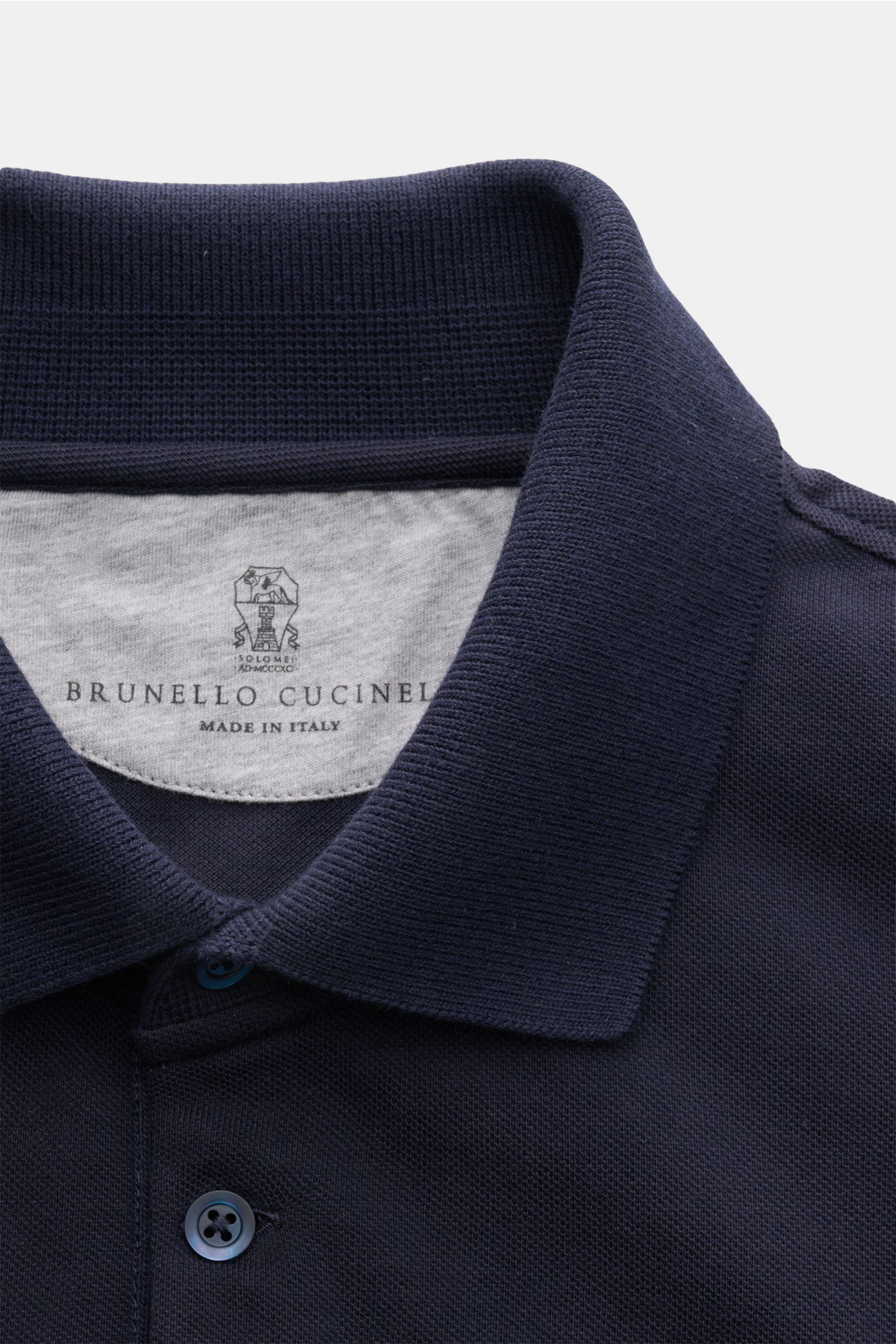 Close-up front view of a navy blue Brunello Cucinelli Poloshirt graublau showing the classic piqué fabric, slim fit, tailored collar, three-button placket, ribbed cuffs with narrow contrast edge, and short side slits. Cleanes Essential erster Wahl: Liebha