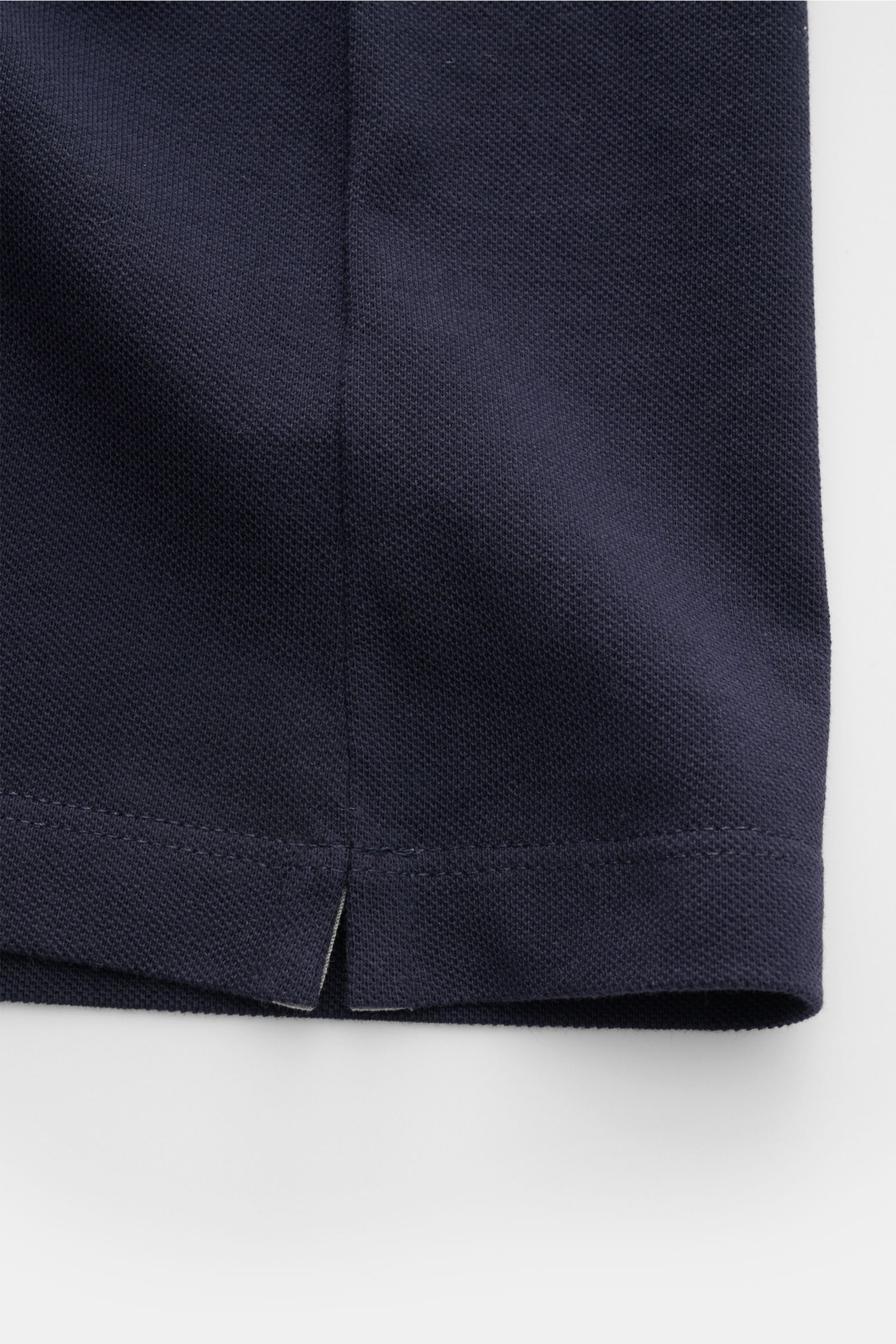 Brunello Cucinelli Poloshirt graublau shown from a close-up side hem perspective, featuring pure cotton piqué, slim fit, tailored collar, three-button placket, ribbed cuffs with contrast edge, and short side slits. Cleanes Essential erster Wahl: Liebhaber