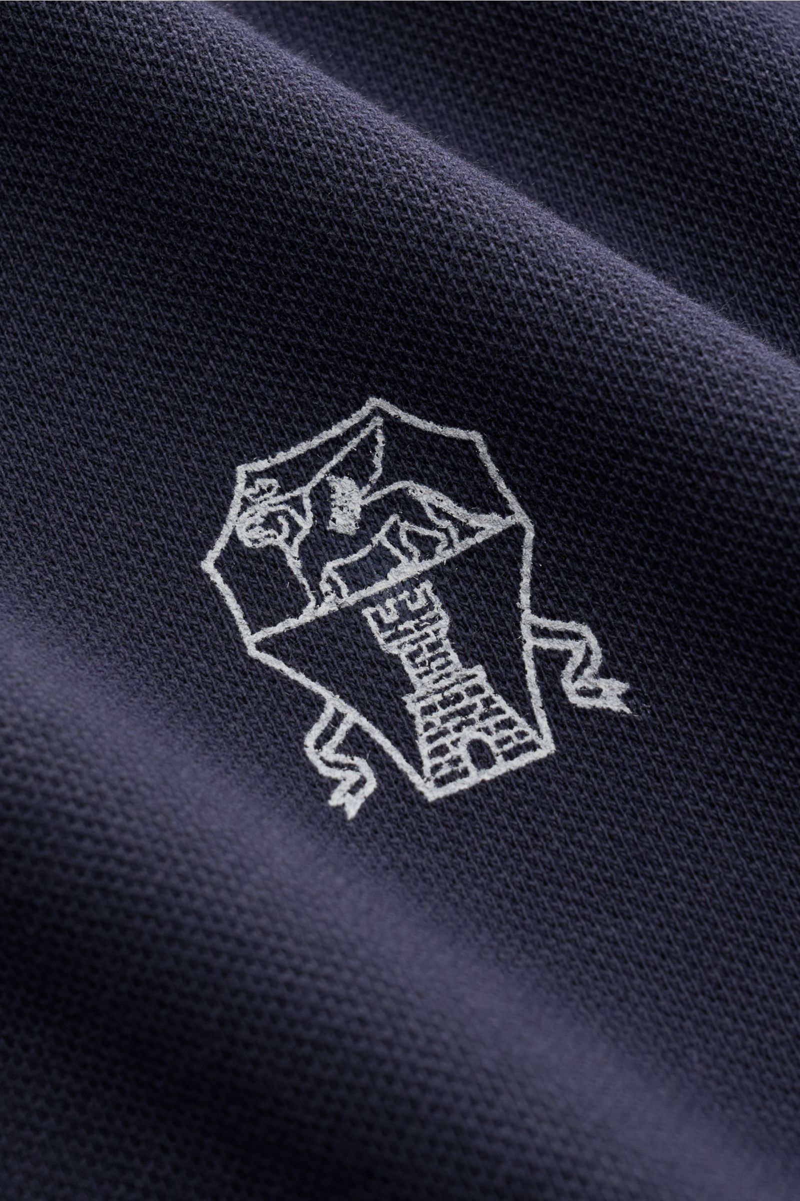 Close-up of the logo embroidery on the Brunello Cucinelli Poloshirt graublau, showing detailed piqué fabric texture from a top-down angle, Cleanes Essential erster Wahl: Liebhaber der Luxusmarke BRUNELLO CUCINELLI sind mit diesem zeitlosen Poloshirt aus k
