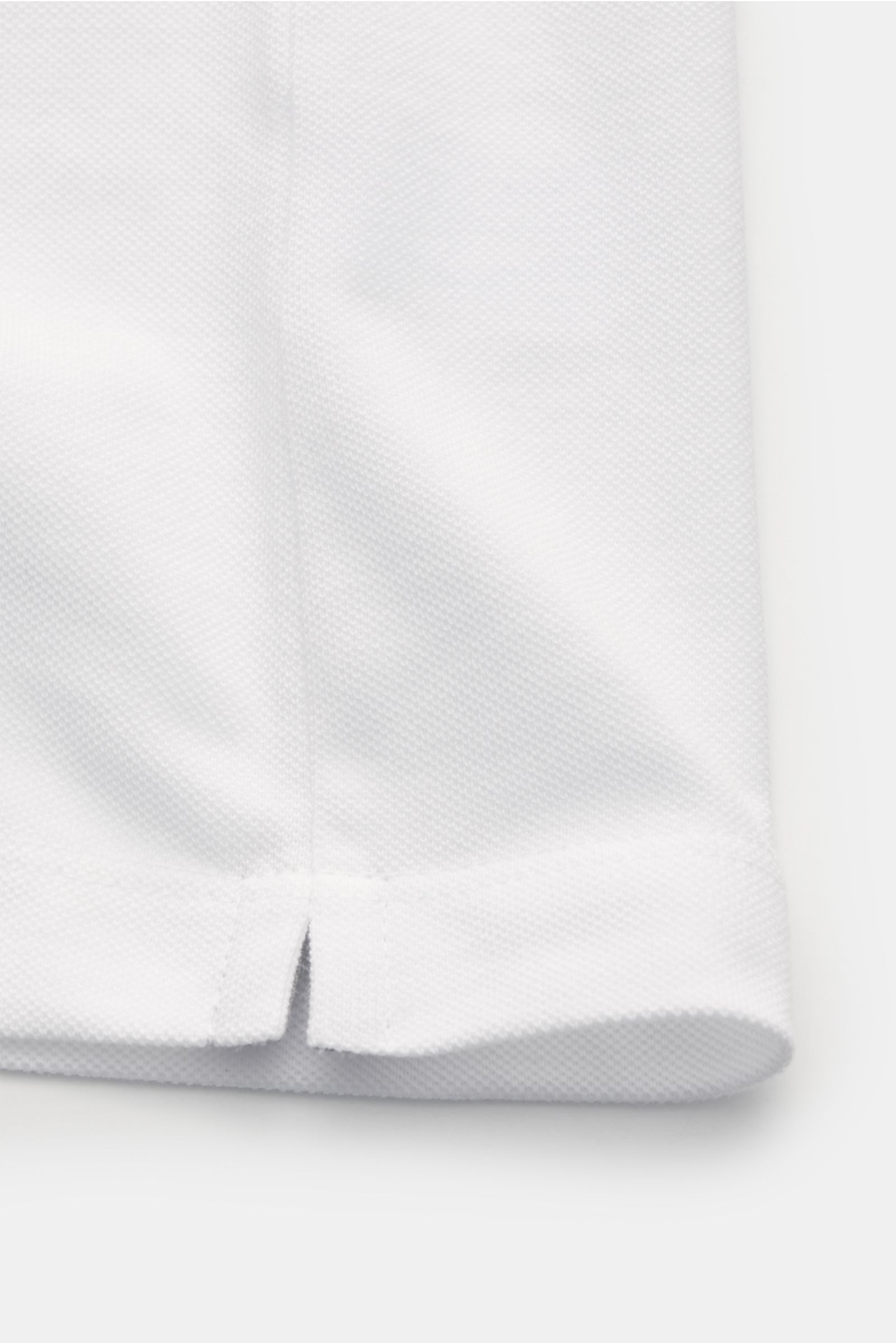 Brunello Cucinelli Poloshirt weiß, Nahaufnahme der kurzen Saumschlitze, Piqué aus reiner Baumwolle, Slim Fit, Rippbündchen mit Kontrastkante.