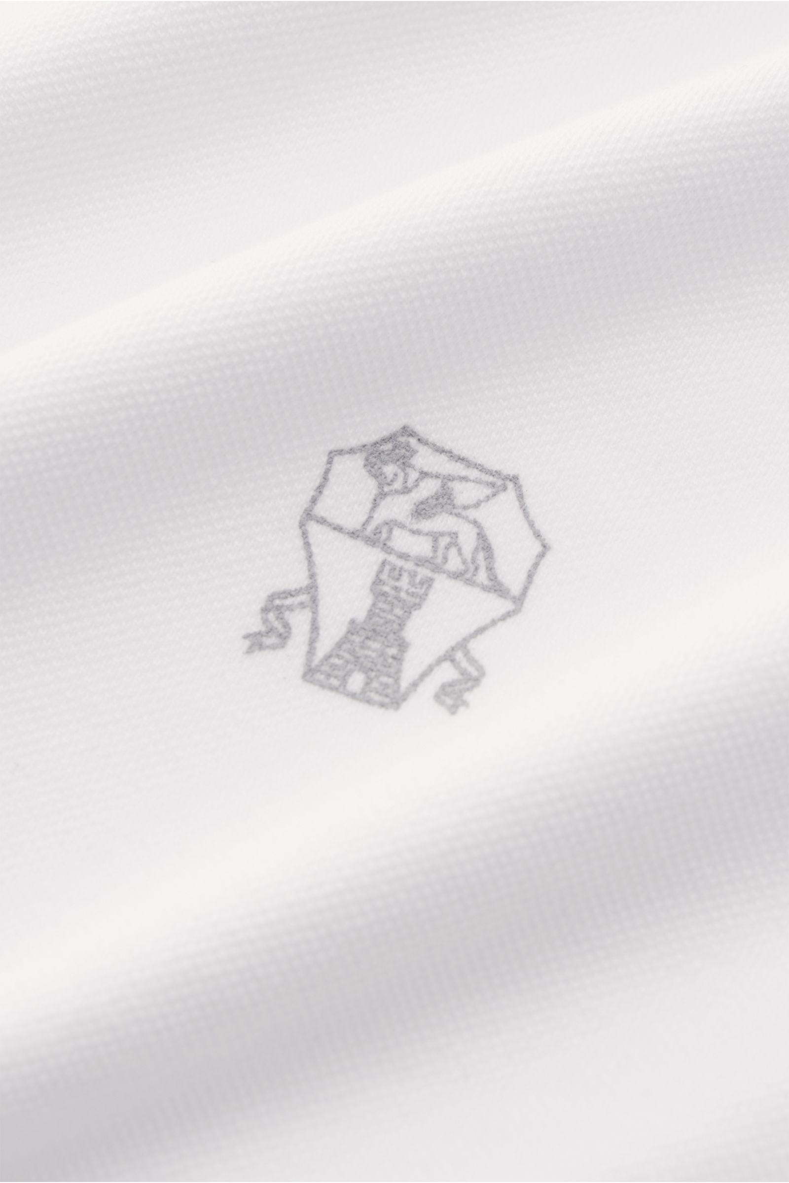 Weißes Brunello Cucinelli Poloshirt Slim Fit aus reiner Baumwolle, klassischer Piqué, Polokragen, Drei-Knopf-Leiste, Logo nah, schräg fotografiert.