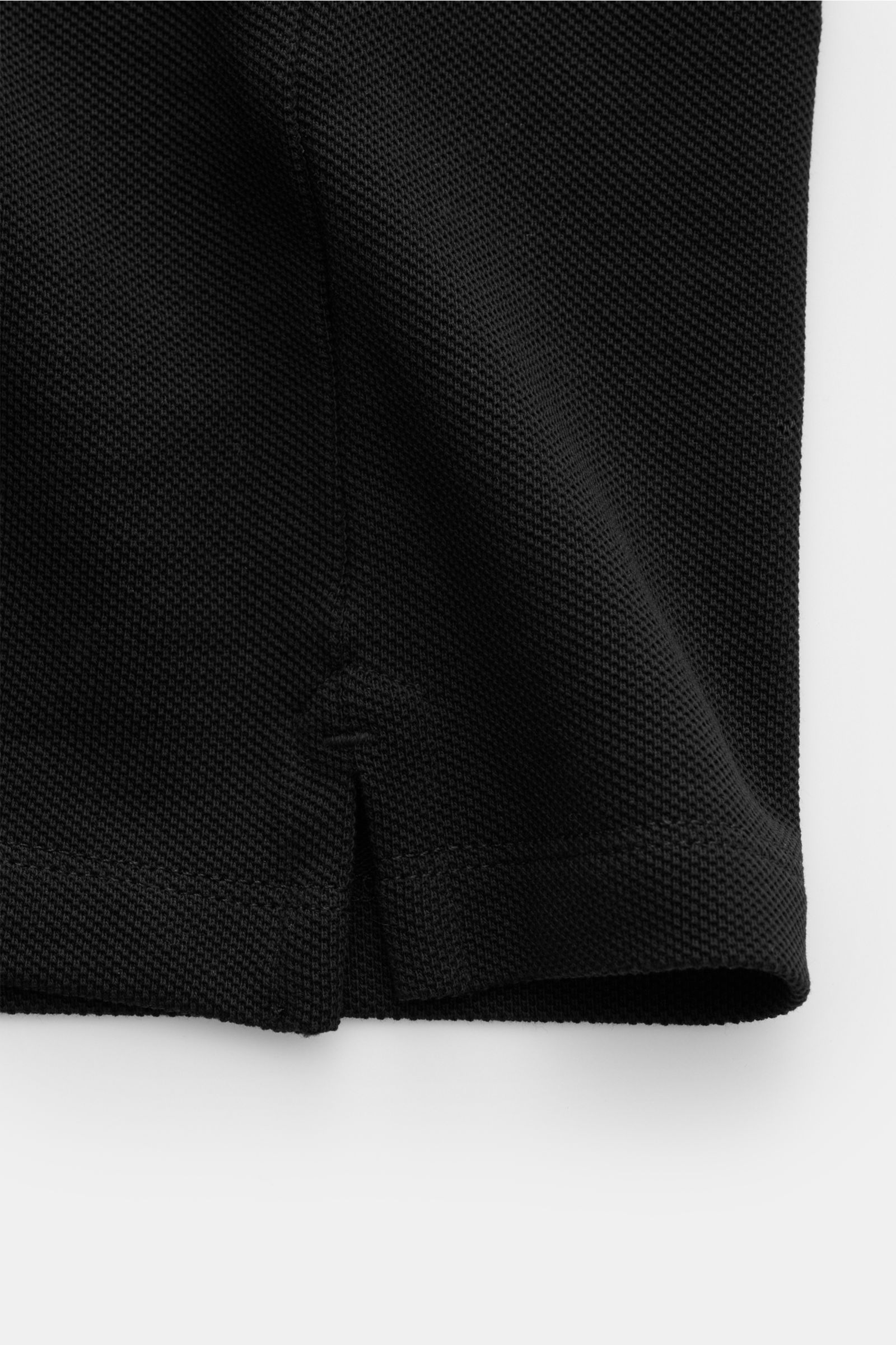 Nahaufnahme des Saumdetails mit kurzem Schlitz vom Ami Paris Poloshirt schwarz aus Piqué Baumwolle, Slim Fit, elastischem Bündchen.