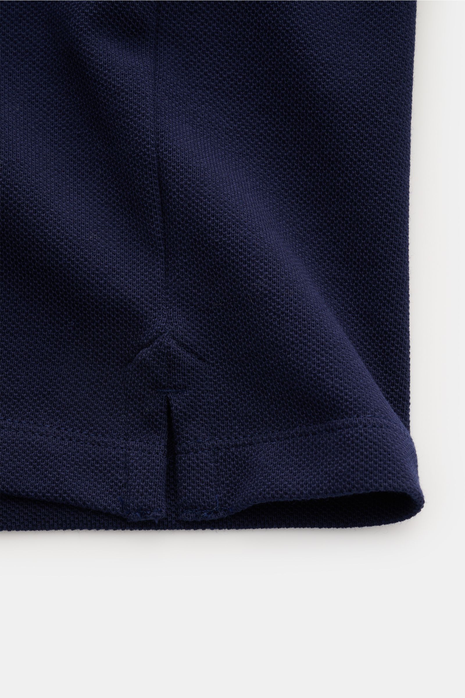 Nahaufnahme des unteren Saums mit kurzem Schlitz des Ami Paris Poloshirt navy aus leicht griffigem Baumwoll-Piqué.
