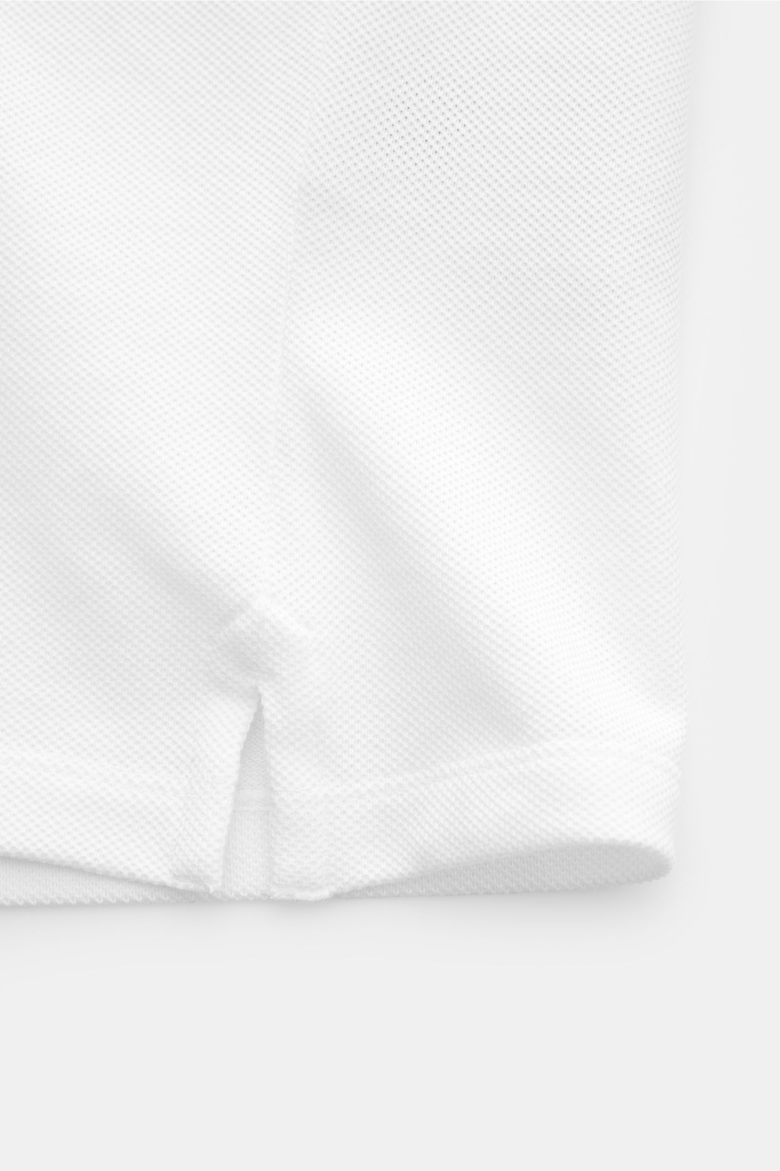 Ami Paris Poloshirt weiß, Slim Fit, aus Baumwoll-Piqué, Detailansicht Saum mit kurzen Schlitzen und leicht griffiger Qualität.