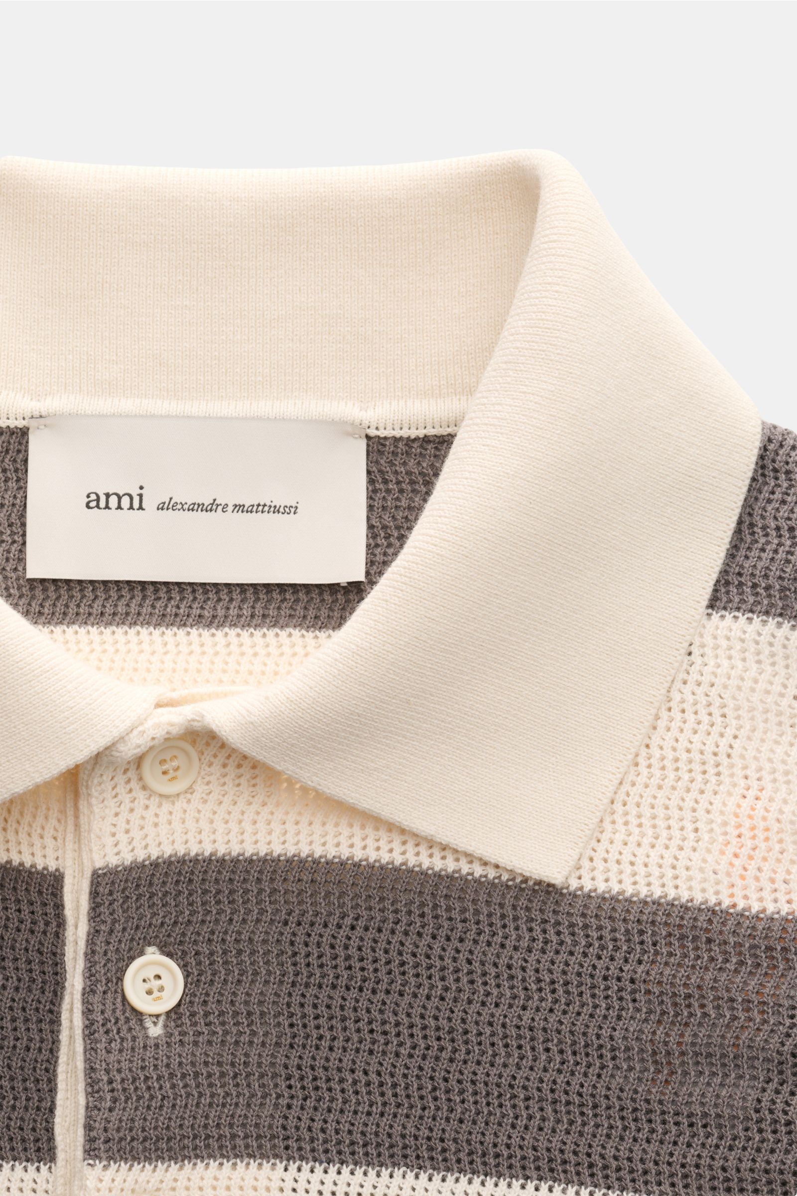 Ami Paris Kurzarm-Strickpolo grau/creme gestreift in Nahaufnahme von oben, aus reiner Baumwolle mit Streifen, Polokragen und Drei-Knopf-Leiste.