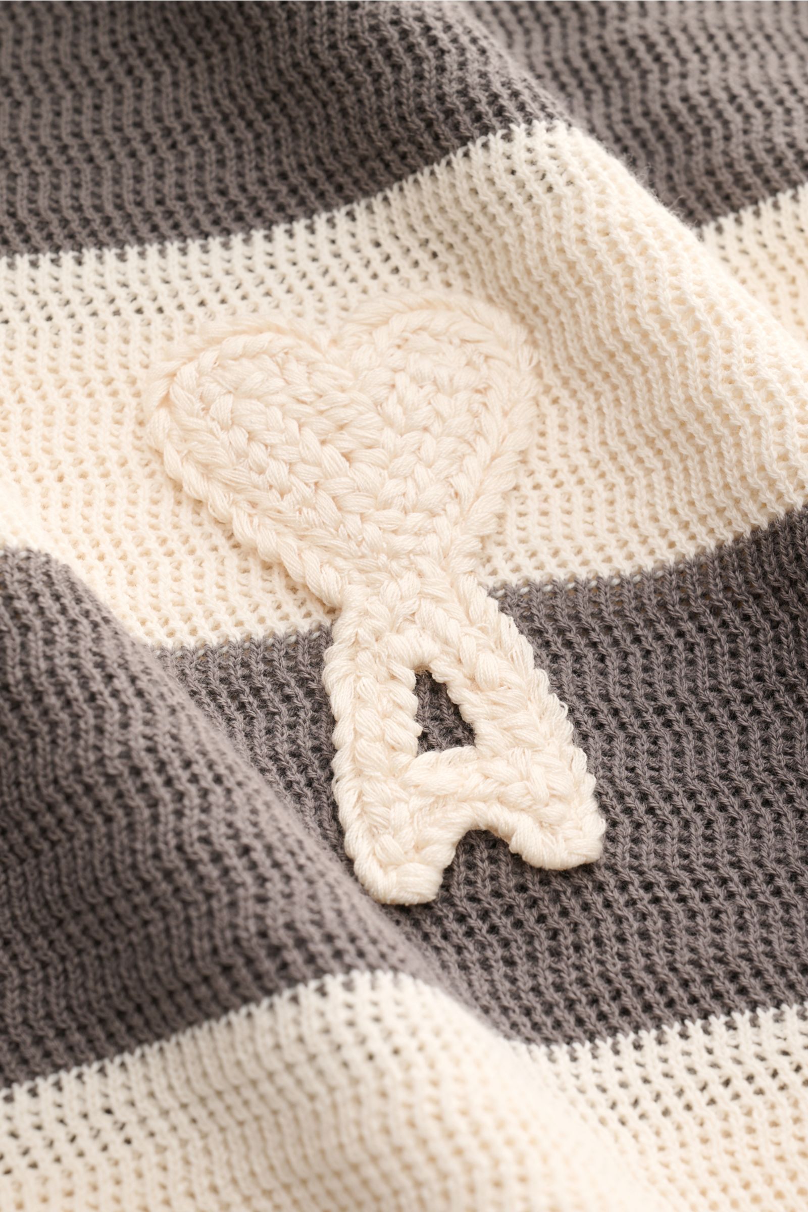 Nahaufnahme des Ami Paris Kurzarm-Strickpolo grau/creme gestreift mit Streifenmuster, griffiger Baumwolle und Herz-Stitching.
