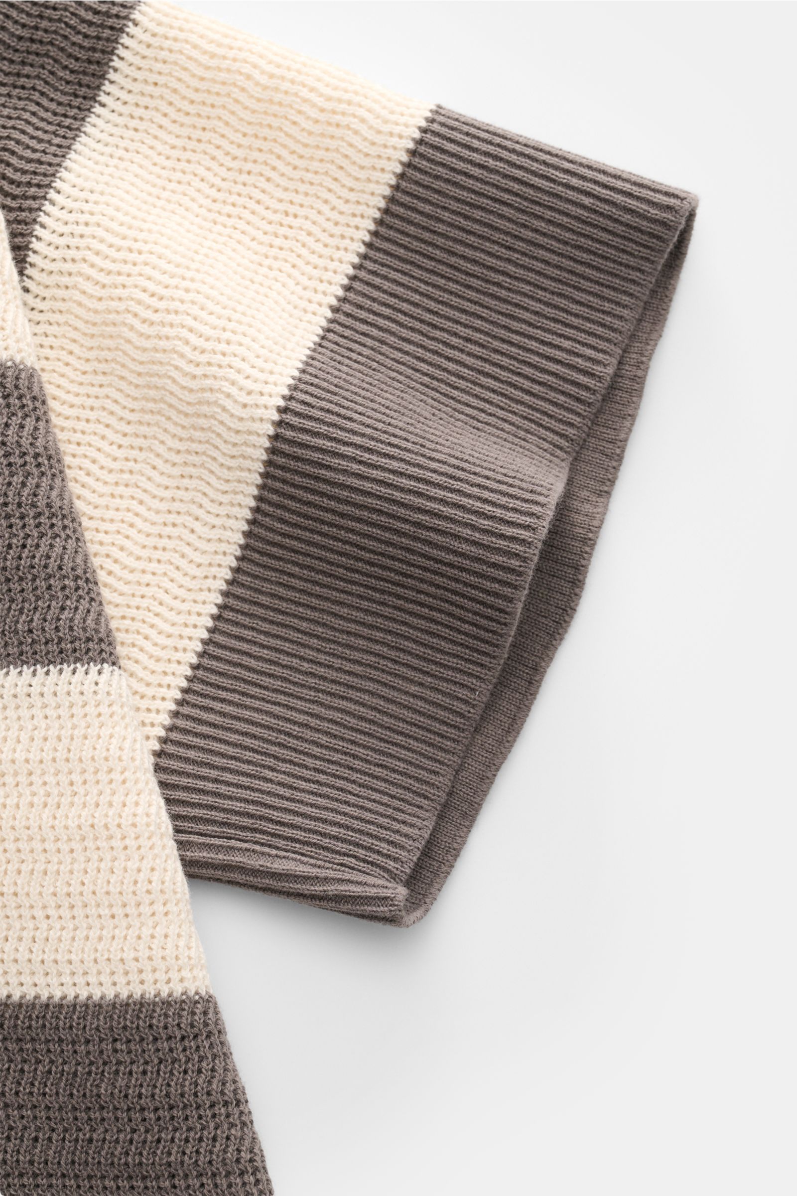 Ami Paris Kurzarm-Strickpolo grau/creme gestreift, aus reiner Baumwolle, Regular Fit, mit Polokragen, Drei-Knopf-Leiste, Herz-Stitching, in Nahaufnahme von der Ärmelperspektive.