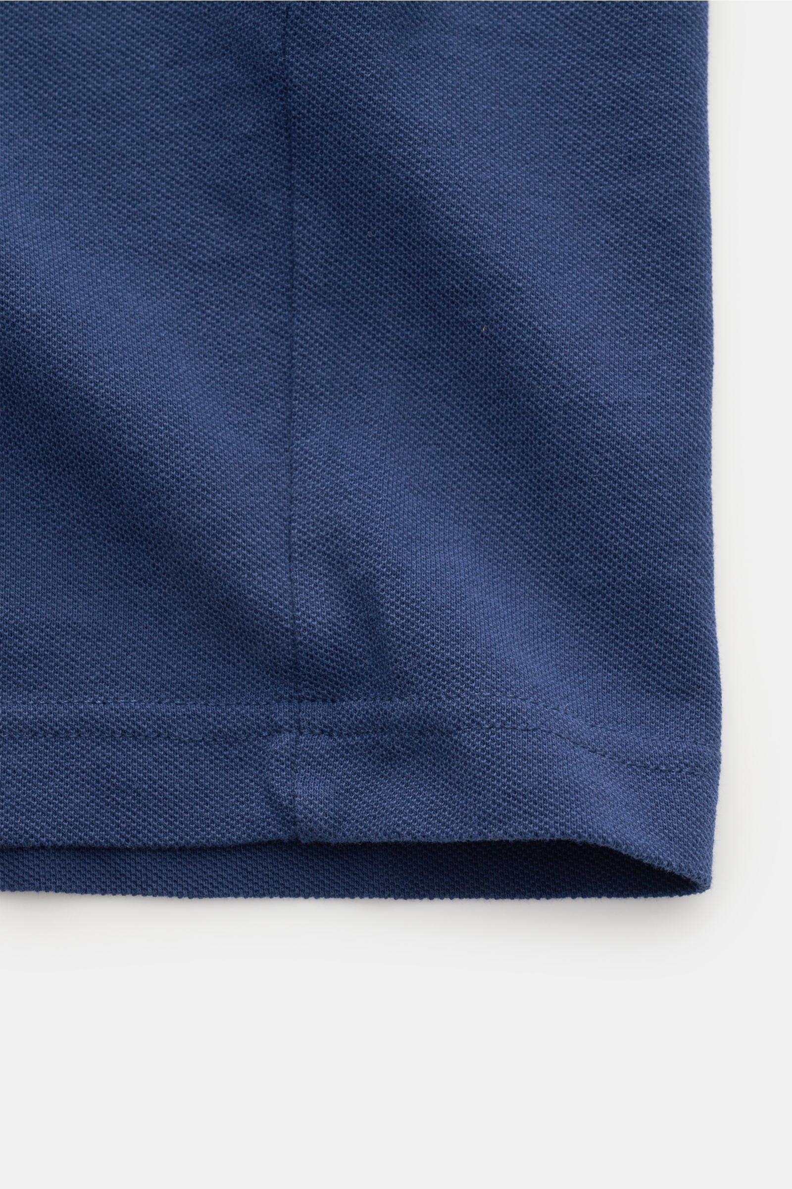 Close-up front view of the hem and fabric texture of the Ami Paris Poloshirt 'Boxy Fit' dunkelblau, a classic with a modern silhouette for casual spring looks. Made of pure cotton with a fine piqué structure, soft touch, oversized fit, typical polo collar