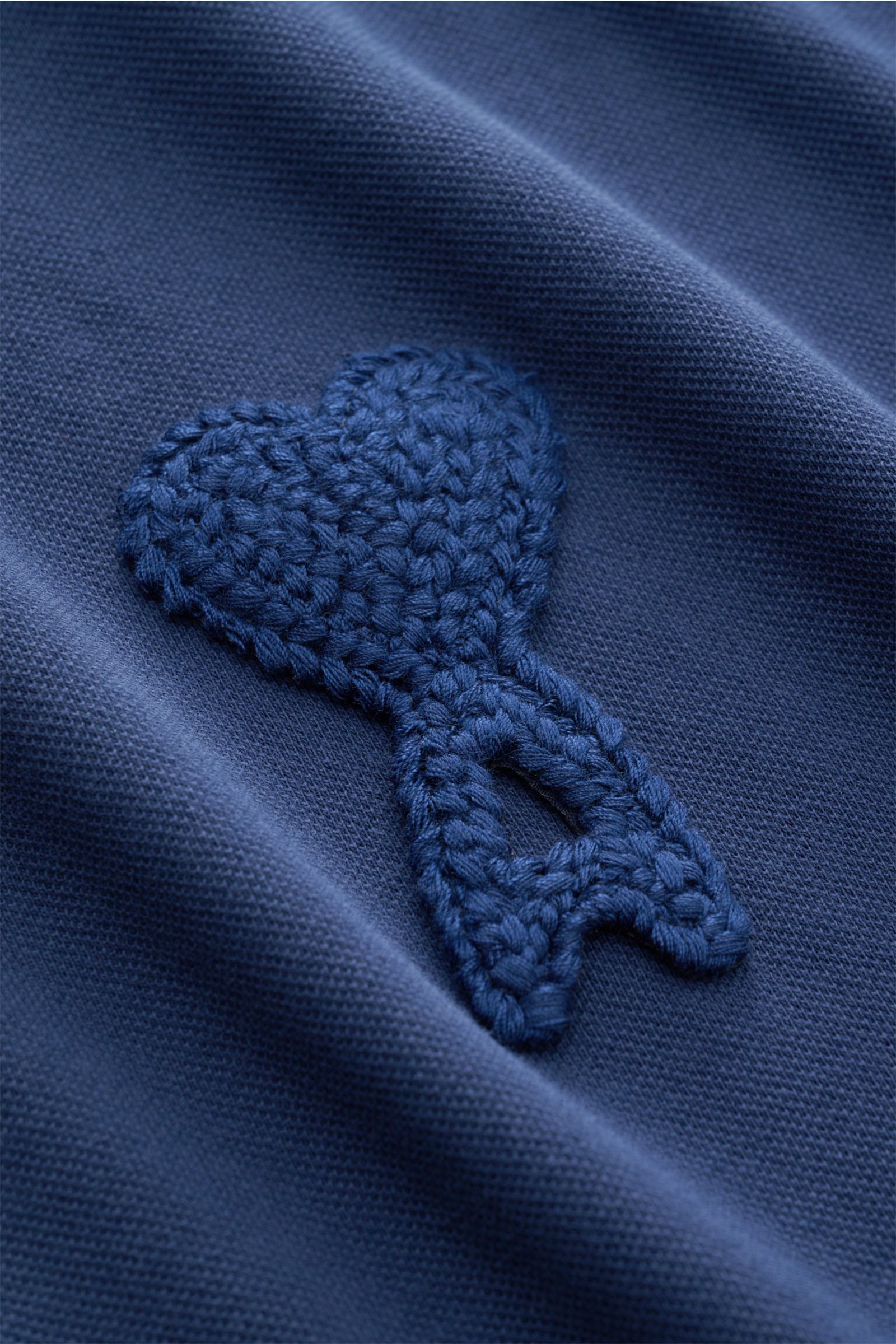 Close-up from a front perspective of the embroidered heart logo on the Ami Paris Poloshirt 'Boxy Fit' dunkelblau, made of pure cotton with fine piqué structure, soft touch, oversized fit, classic polo collar, three-button placket, and signature logo stitc