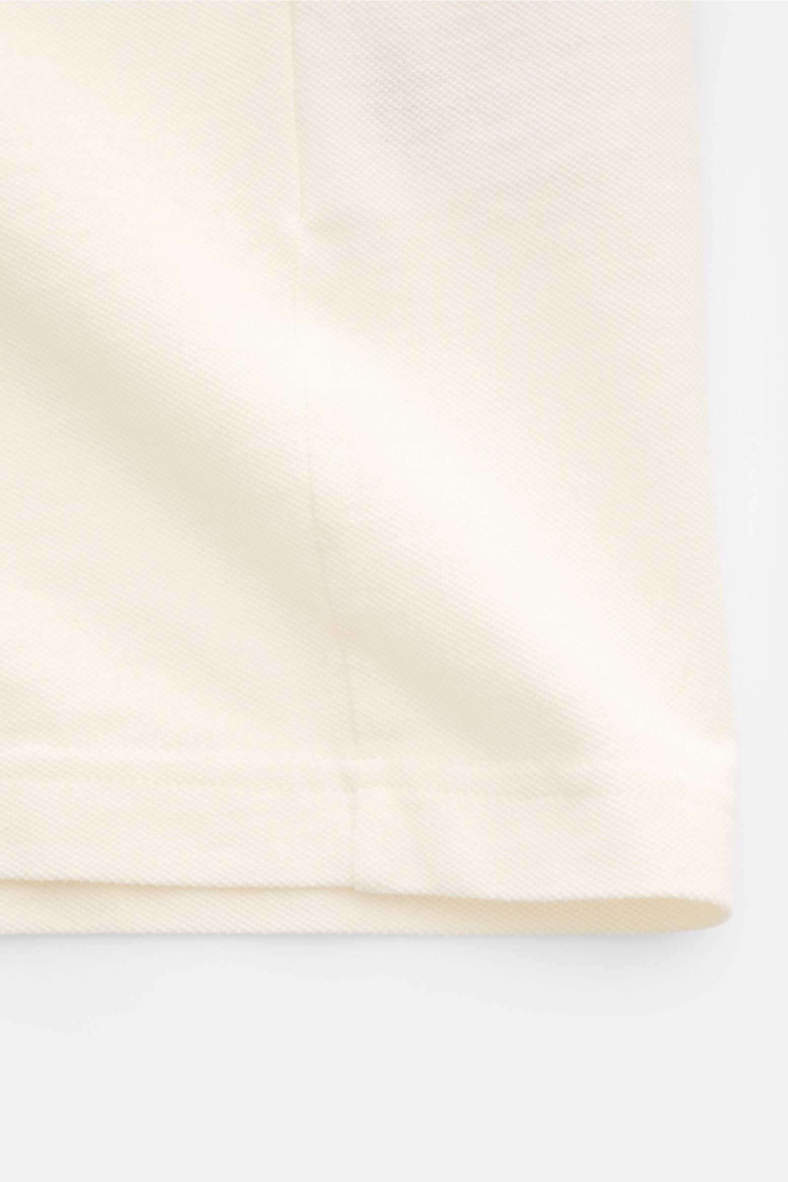 Ami Paris Poloshirt 'Boxy Fit' creme in Nahaufnahme von unten, reine Baumwolle, feine Piqué-Struktur, weicher Griff, Oversized Fit, Polokragen, Drei-Knopf-Leiste, Logo-Stitching.