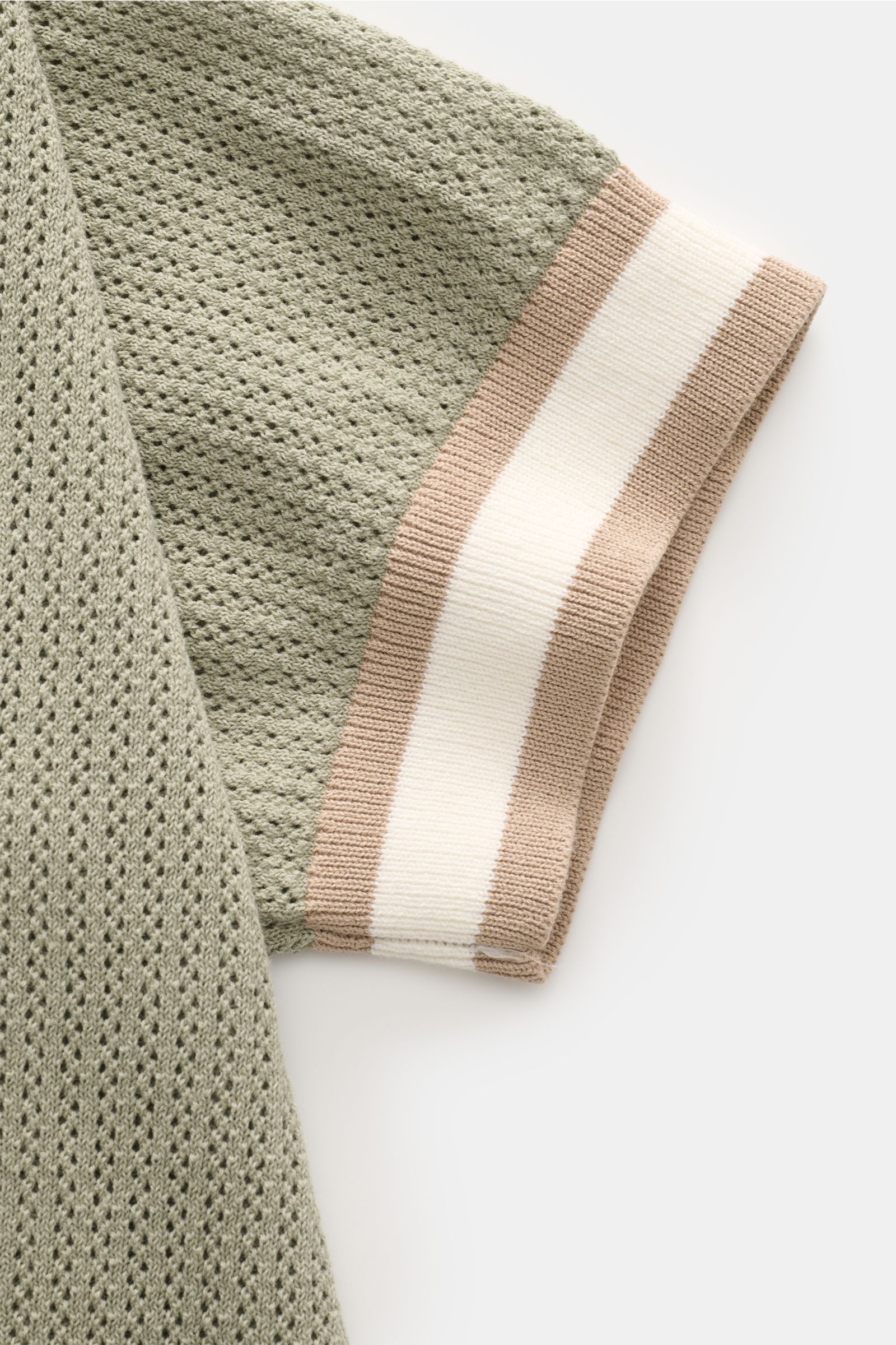 Nahaufnahme des Ärmels vom Ché Kurzarm-Strickpolo 'Quinn' salbei mit luftigem Strickmuster und gestreiften Rippbündchen, seitliche Perspektive.