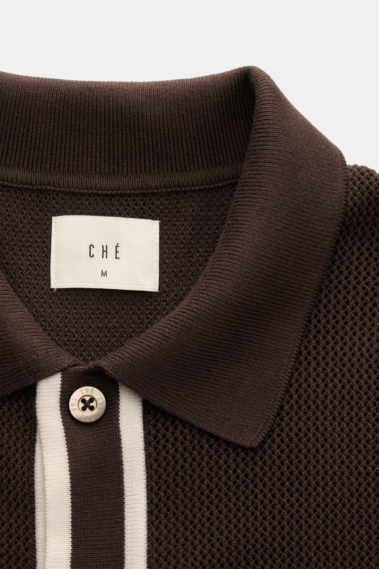 Close-up front view of Ché Kurzarm-Strickhemd 'Jorge' dunkelbraun showing dark brown knit polo with white contrast stripes, pearl-effect button, and folded collar. Ob offen über einem T-Shirt oder geschlossen getragen – das gestrickte Kurzarmhemd 'Jorg