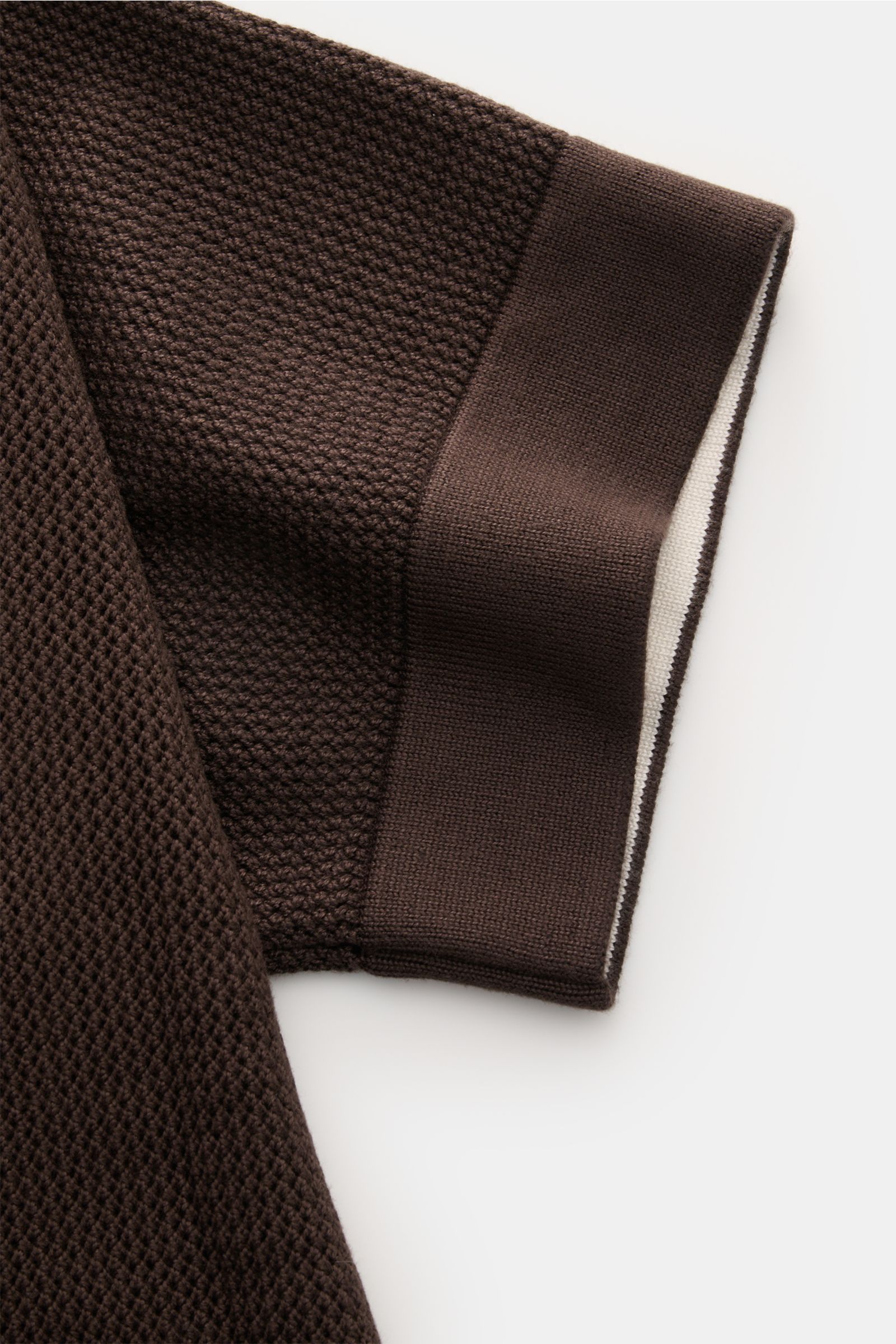 Close-up side view of the sleeve of the Ché Kurzarm-Strickhemd 'Jorge' dunkelbraun, showing fine, airy knit texture with a heavy, grippy quality and a comfortable ribbed cuff with a white contrast stripe. Ob offen über einem T-Shirt oder geschlossen ge
