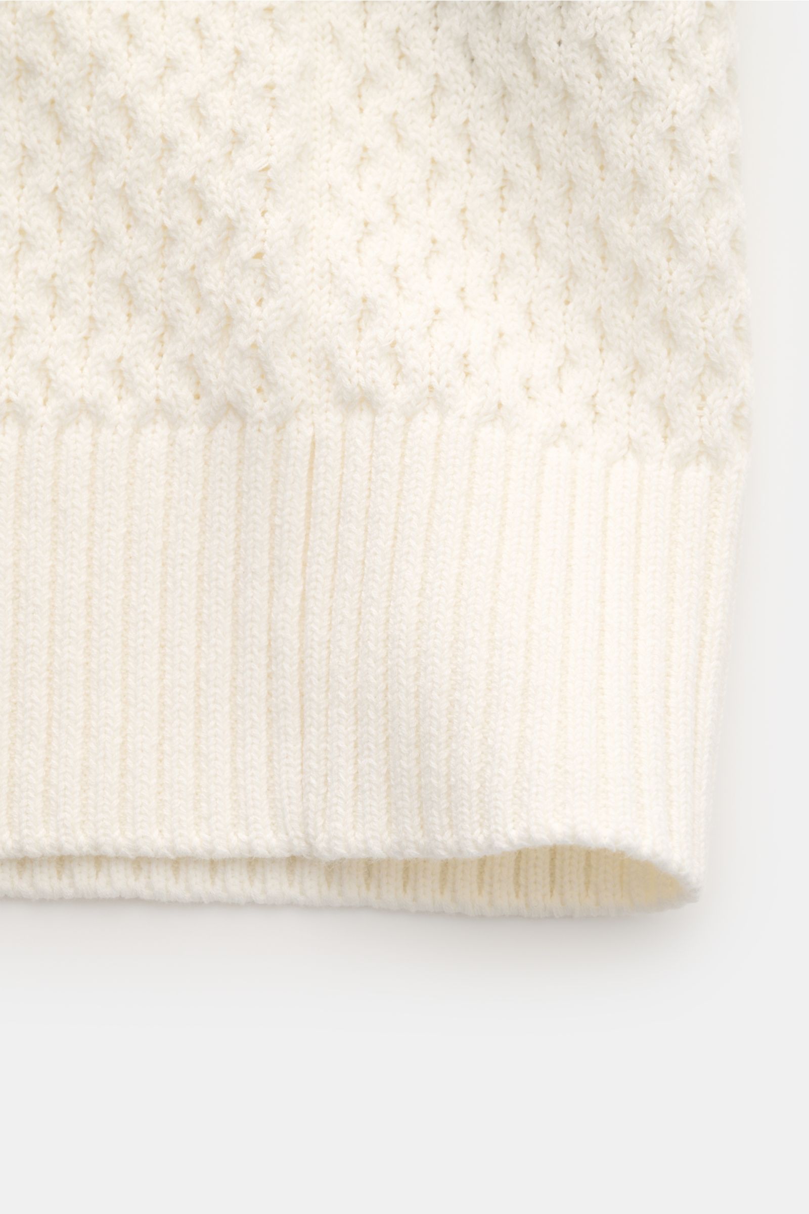 Close-up front view of the Ché Kurzarm-Strickpolo 'Santino' creme, showcasing its thick cream cotton knit with an asymmetrical pattern and ribbed cuffs. Strickkunst mit Twist: Das 'Santino' Kurzarm-Poloshirt von CHÉ überzeugt mit einem groben Muster mit a