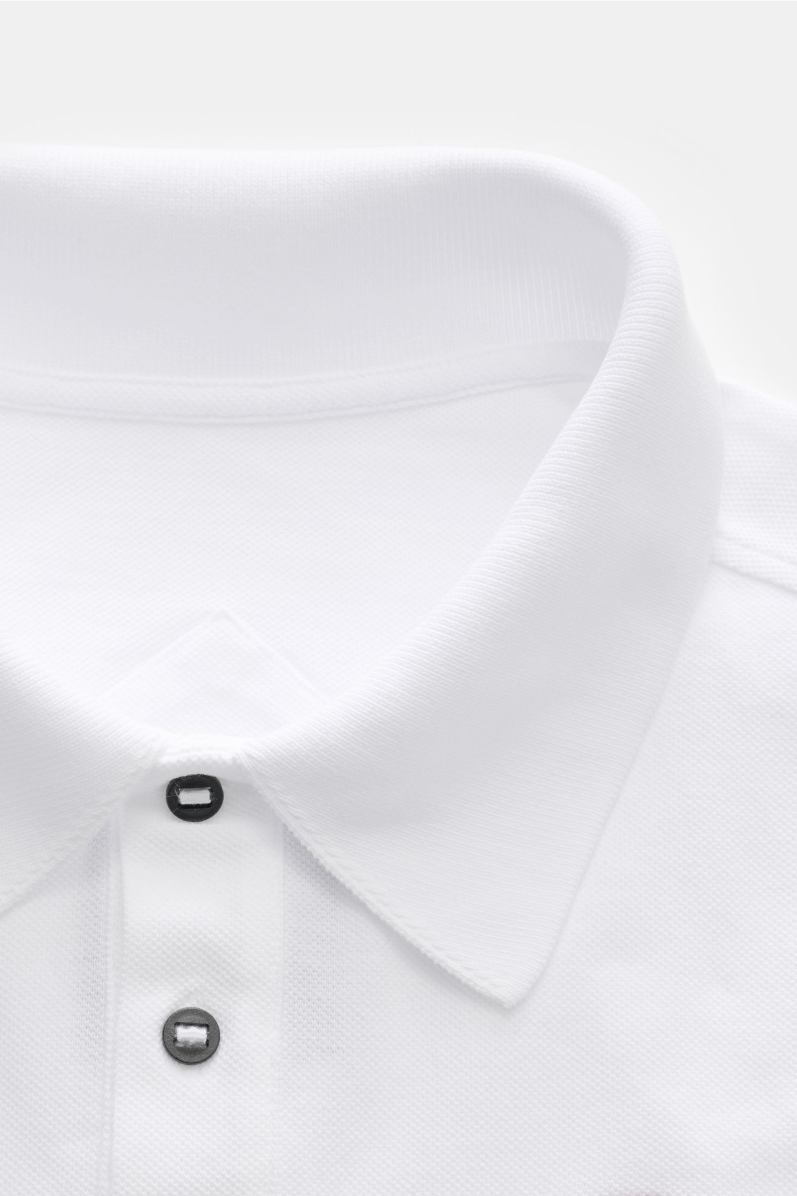 Close-up front view of the Canada Goose Poloshirt 'Beckley' weiß, a classic white polo made of pure cotton piqué with a structured feel, garment dyed fabric, regular fit, typical polo collar, three-button placket, Canada Goose patch on the chest, flexible