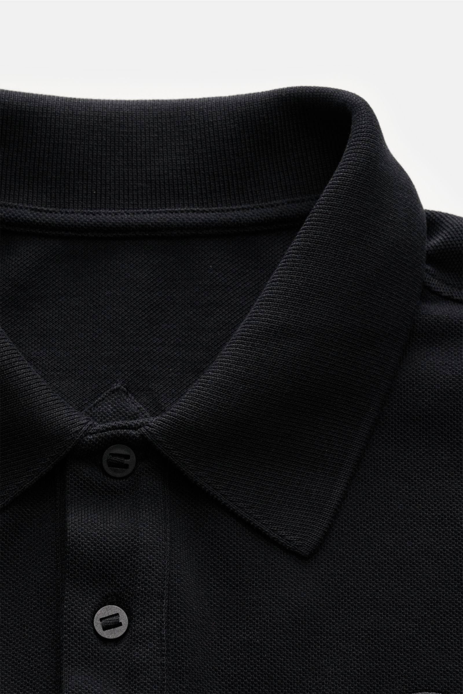 Close-up front view of the Canada Goose Poloshirt schwarz showing the classic polo collar, three-button placket, and textured black cotton piqué fabric.

Description: Das klassische Poloshirt ist ein Must-have in der sportiven Herrengarderobe: Aus Baum