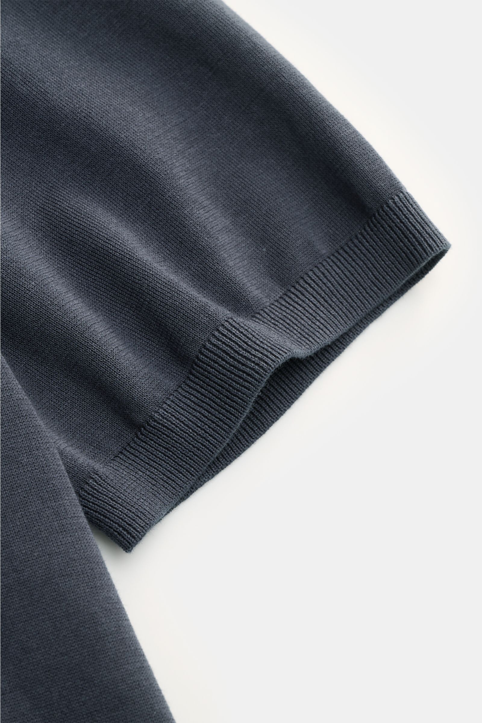 Nahaufnahme des Closed Kurzarm-Strickpolo graublau, feiner Baumwoll-Feinstrick mit weichem Griff und komfortablem Rippbündchen, seitliche Perspektive.