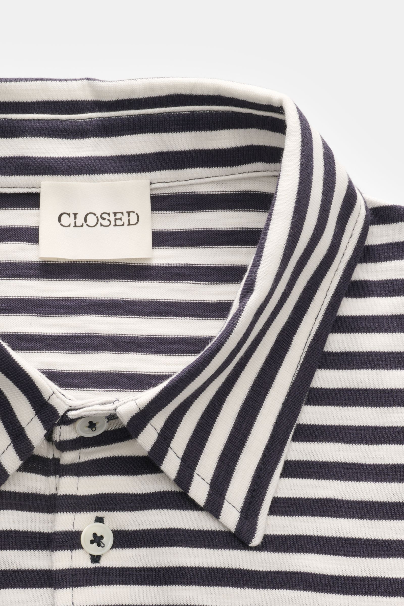 Close-up front view of the Closed Short sleeve knit polo dark navy/cream striped with a signature polo collar and three-button placket.

This CLOSED short sleeve knit polo is made from pure, soft cotton and is a sporty essential for the new season.