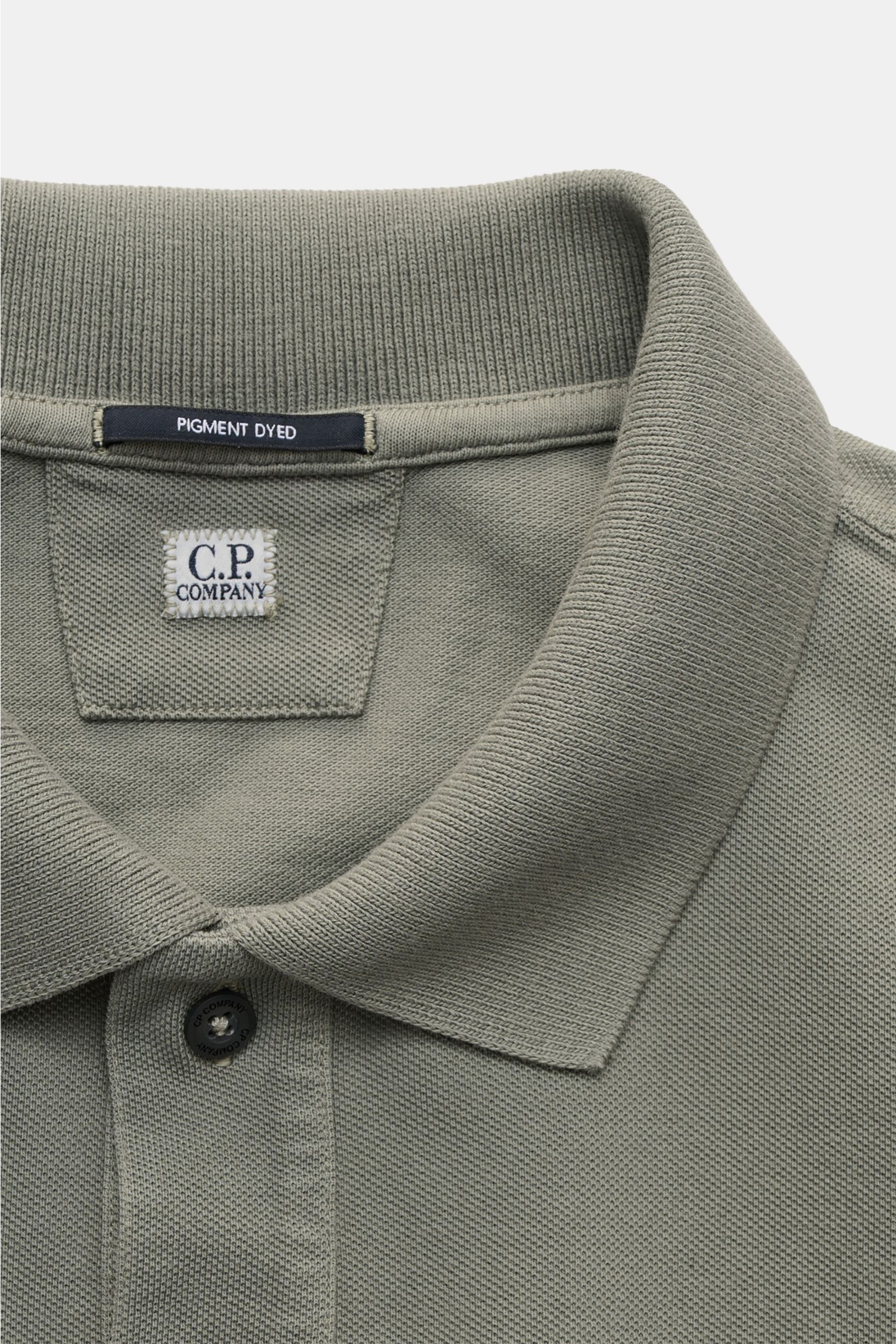 C.P. Company Poloshirt grau, Nahaufnahme von oben, Baumwoll-Piqué, Pigment-Dye, klassischer Polokragen, Zwei-Knopf-Leiste, kleines Weblabel auf der Brust.