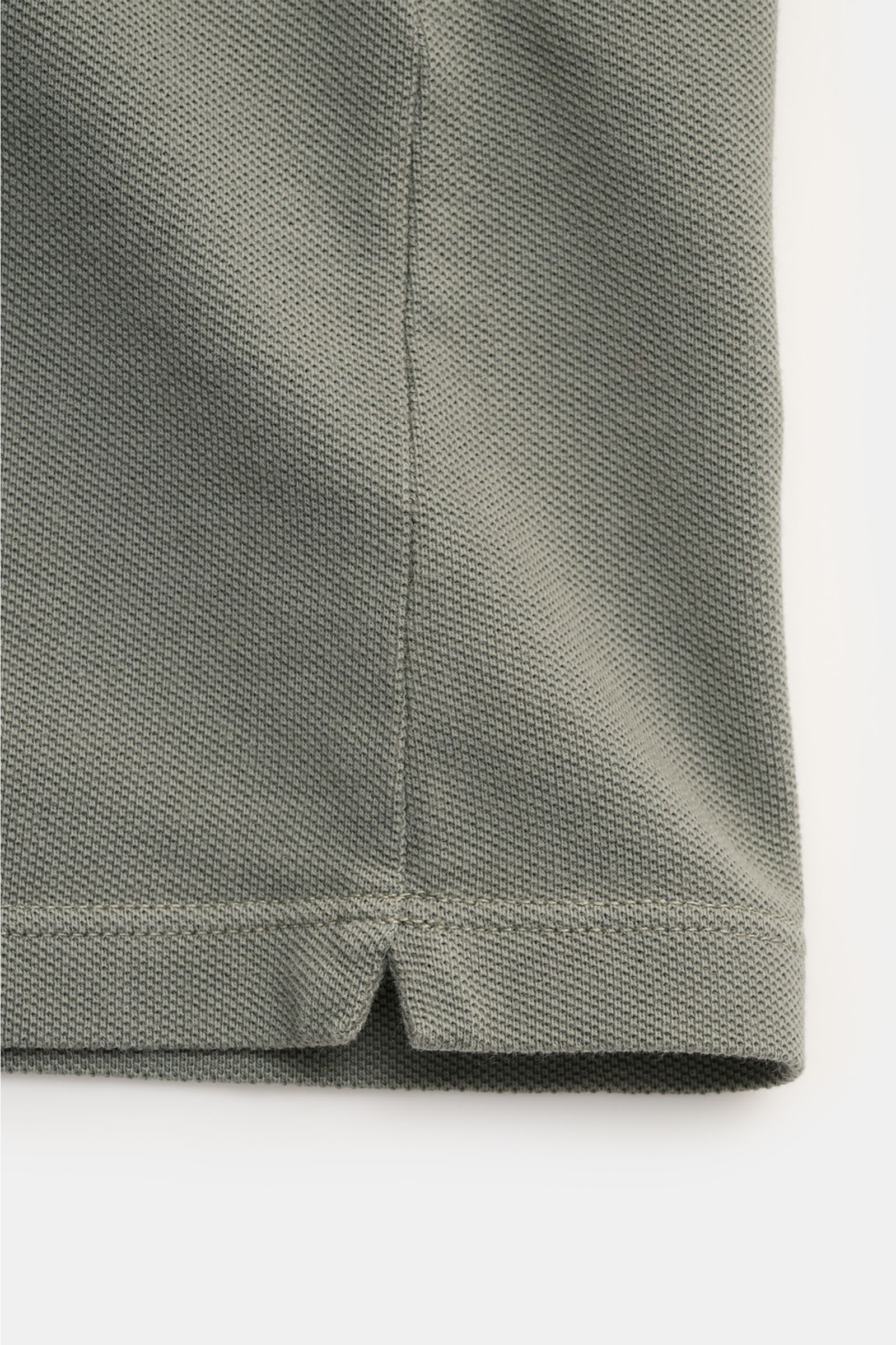 C.P. Company Poloshirt grau, Nahaufnahme der Piqué-Baumwollstruktur und kurzen Saumschlitze, seitliche Perspektive, Slim Fit, elastische Ärmelbündchen.