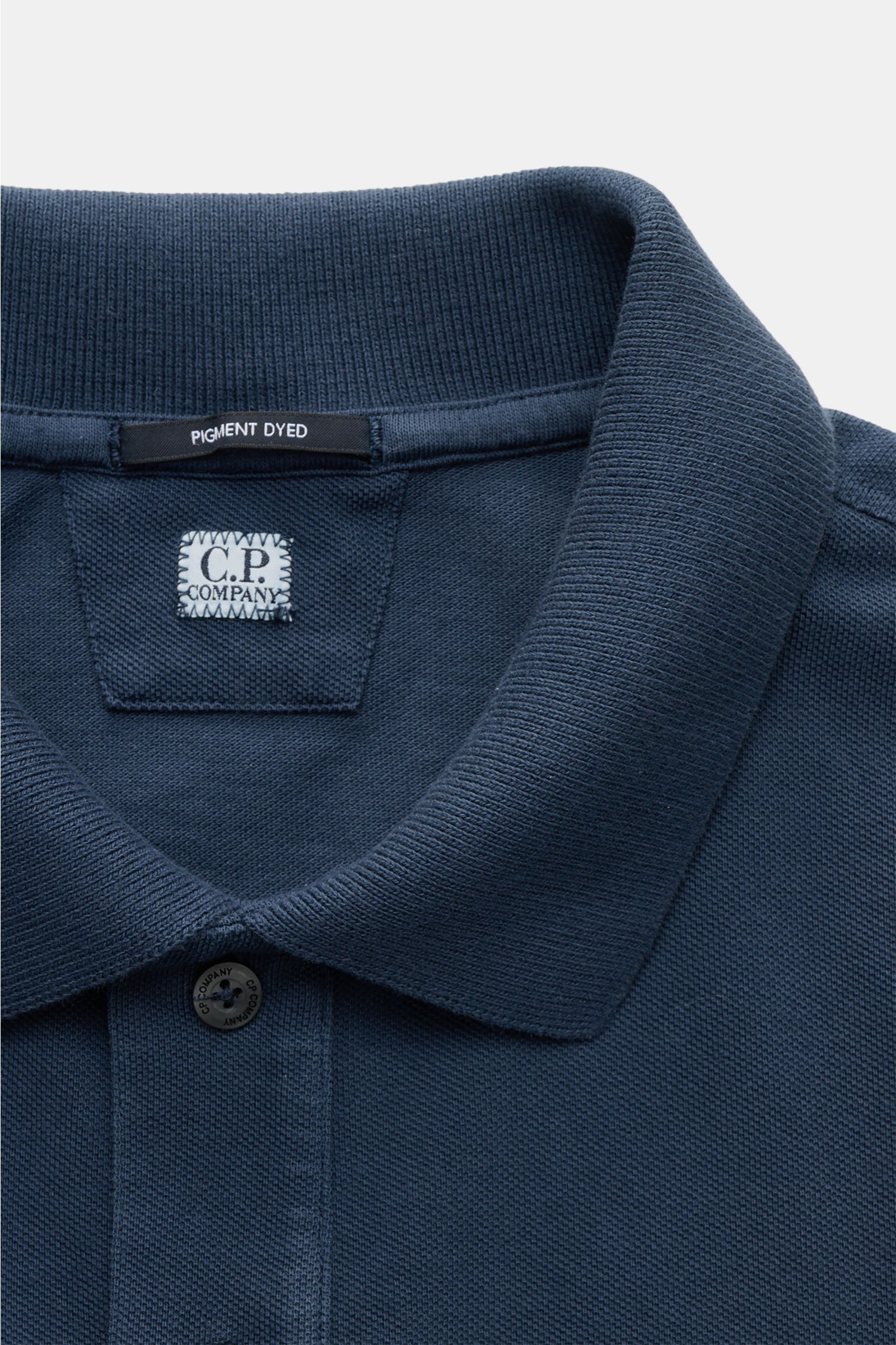 C.P. Company Poloshirt dunkelblau in Nahaufnahme von oben, Baumwoll-Piqué, klassischer Polokragen, Pigment-Dye-Färbung, feines Stitching.